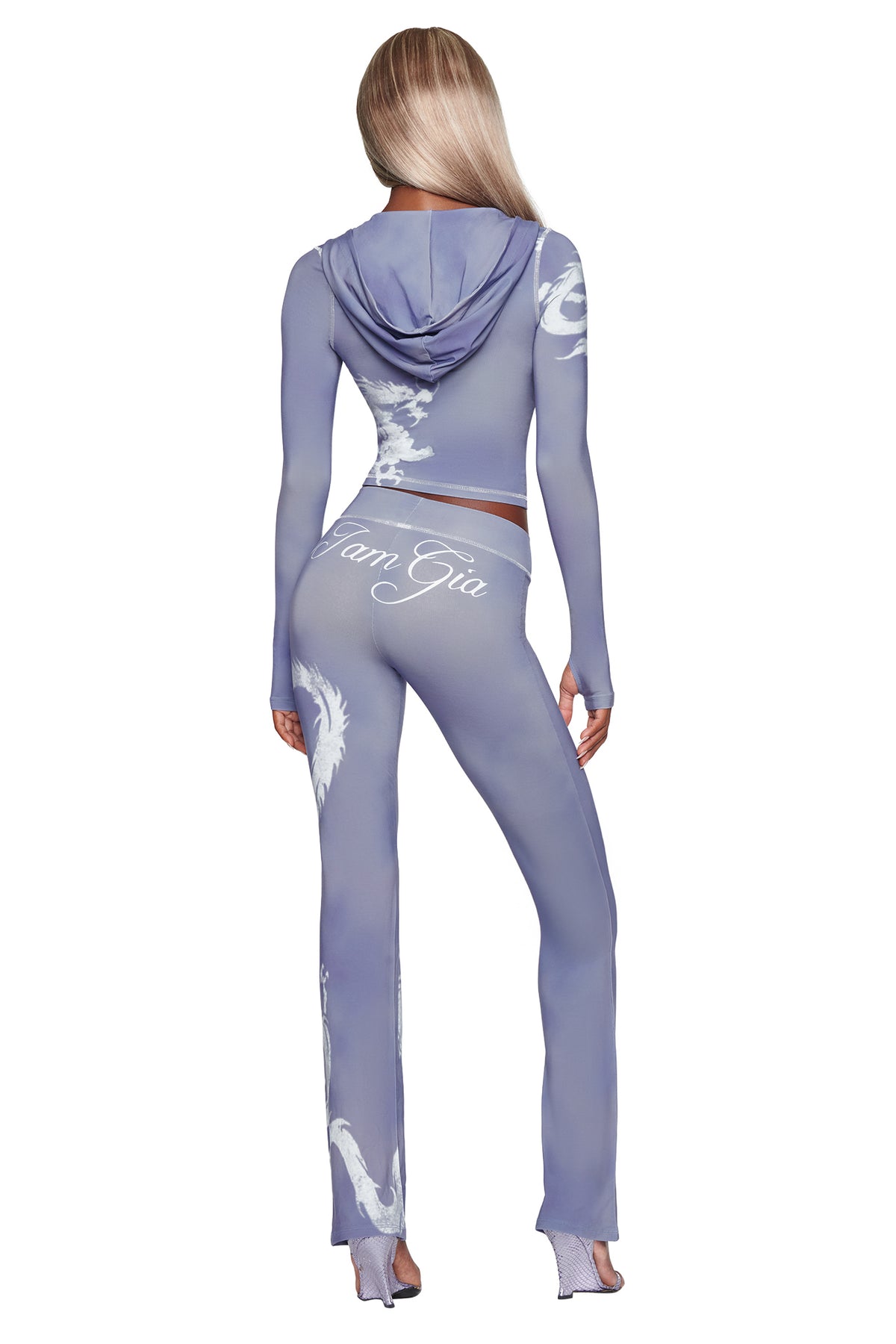A woman with long blonde hair stands with her back to the camera against a white background, wearing the I.AM.GIA BLARE HOODIE - STEEL BLUE DRAGON. The fitted hoodie features a subtle steel blue dragon motif woven into its bamboo fabrication and showcases bold white “I am Gia” text and dragon designs on the back for an extra touch of style.