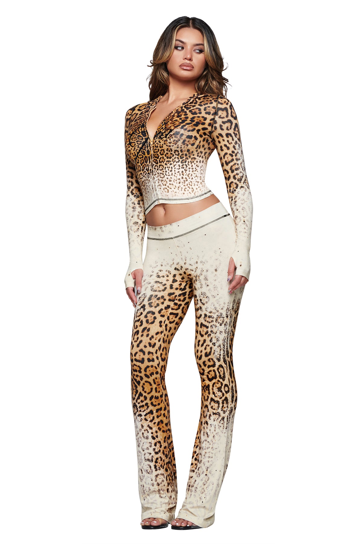 A woman stands against a white background wearing the I.AM.GIA BLARE TRACKPANT in Cream Faded Panthera, a fitted, long-sleeve leopard print top and matching ombre-effect trackpants crafted from soft bamboo fabric.