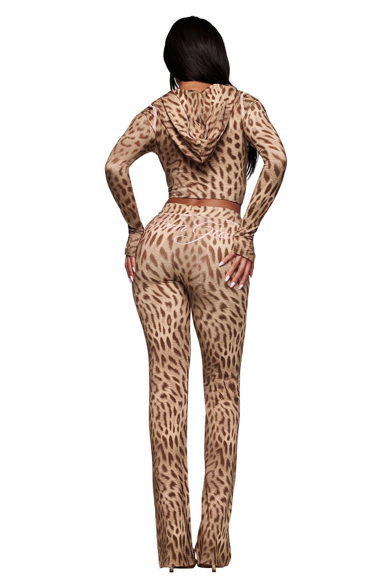 A woman faces away from the camera wearing the I.AM.GIA BLARE TRACKPANT in Blaze Cheetah—this fitted, hooded two-piece set features a tan and brown animal print, long sleeves, and flared leg pants for a bold, stylish look.