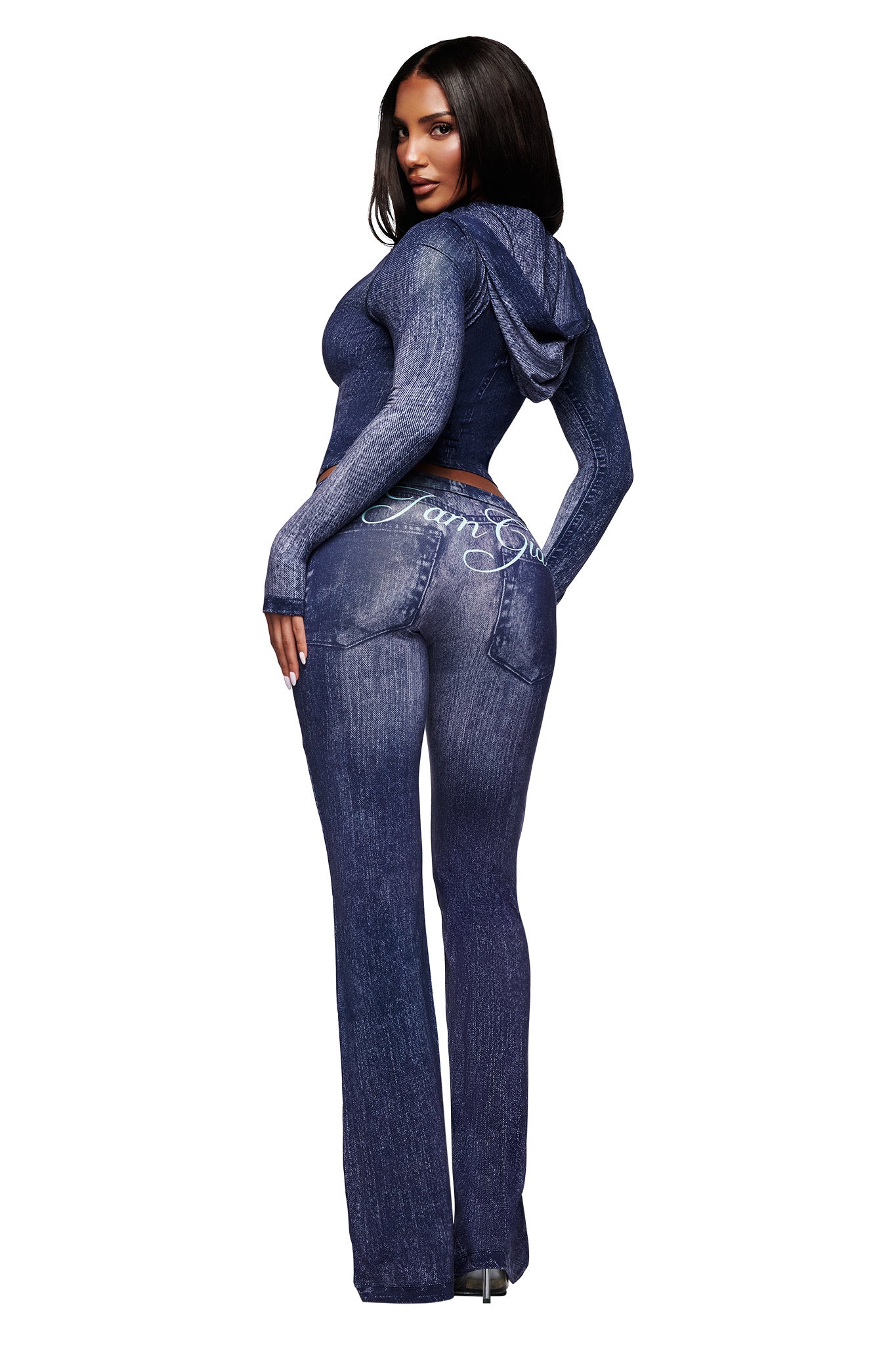 A woman with long dark hair models the I.AM.GIA BLARE TRACKPANT - DARK DENIM set, featuring a denim-patterned hooded jacket and matching faux-denim pants with "Baby Girl" script on the back pocket, against a white background.
