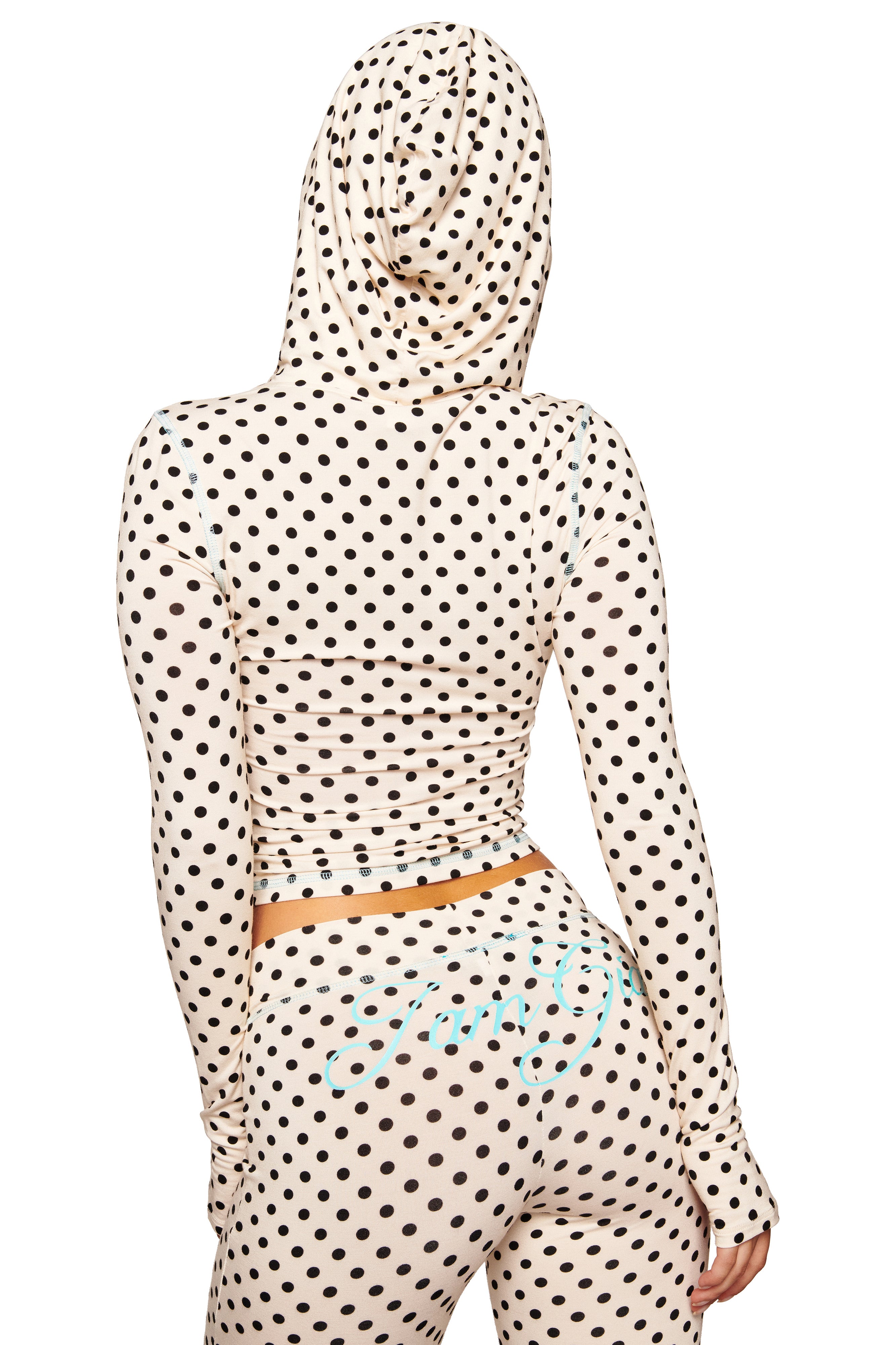 A person is seen from the back wearing the I.AM.GIA BLARE HOODIE in cream polka dot with a bodycon fit. The hood is up, and the matching set includes pants with light blue script detailing.