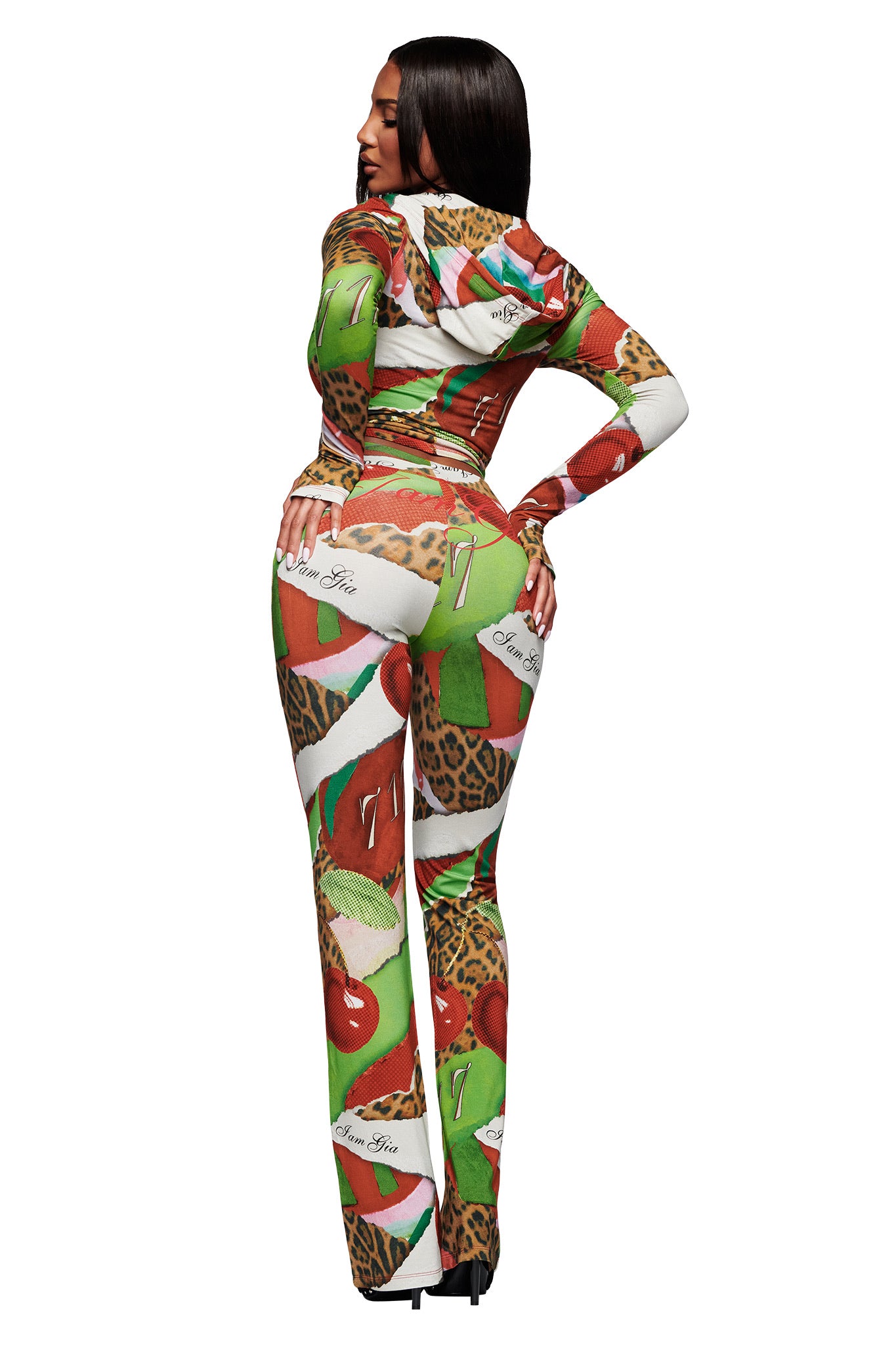 A woman with long dark hair poses with one hand on her hip, wearing the I.AM.GIA BLARE TRACKPANT in Wild Cherry—a vibrant, form-fitting trackpant featuring bold animal prints and colorful design elements.