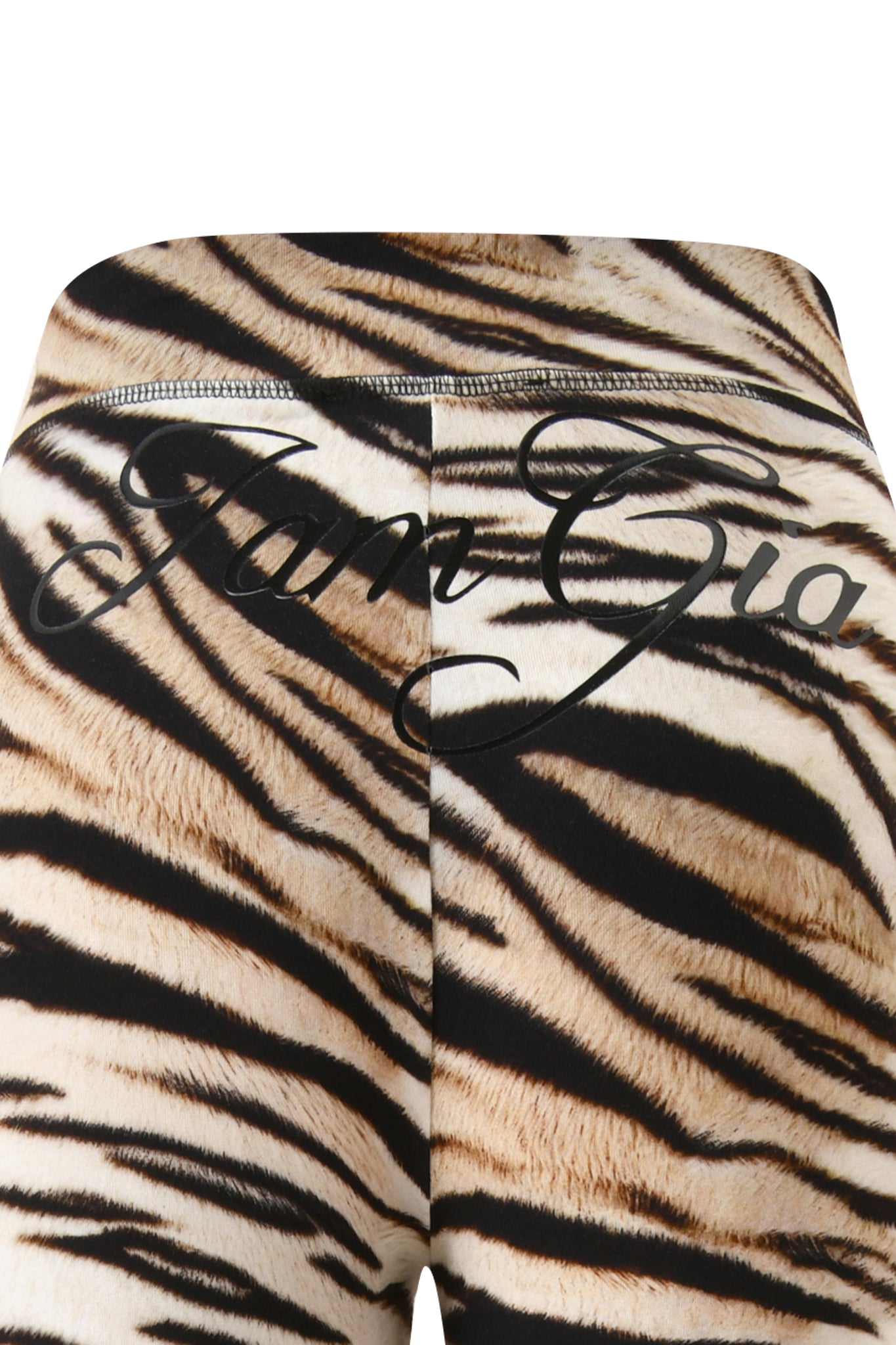 Close-up of the back of the I.AM.GIA BLARE TRACKPANT - LIGHT TIGRESS, featuring bold black "I.AM.GIA" script across the waistband and upper back on tiger-print fabric.
