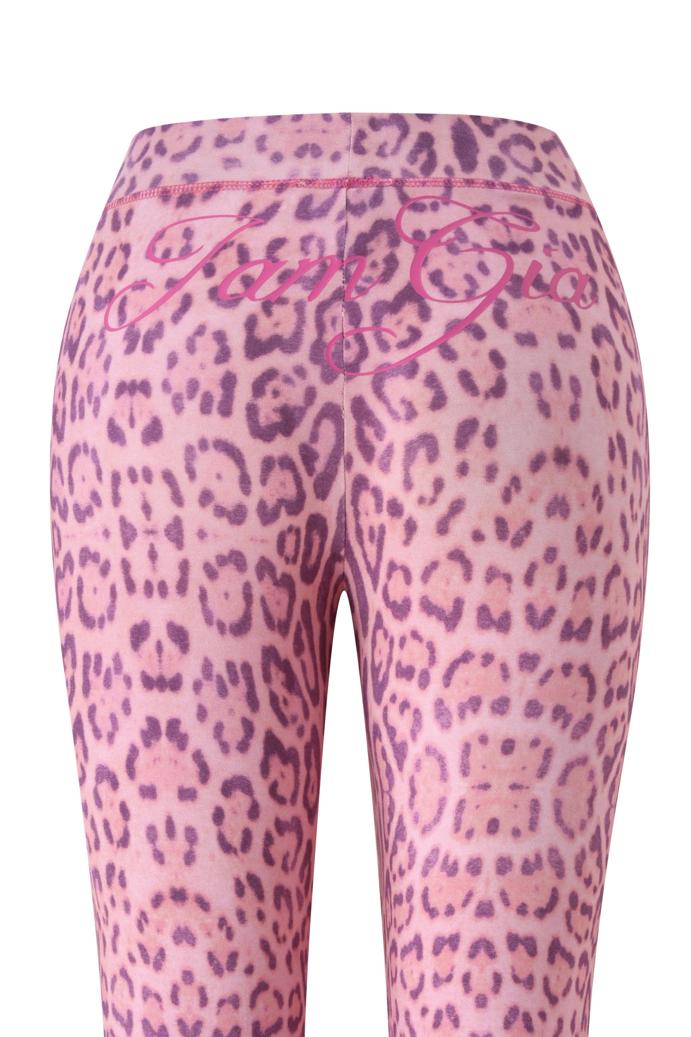 The BLARE TRACKPANT - PINK PANTHERA by I.AM.GIA features purple leopard-print leggings with "Tan Gia" in cursive on the waistband, shown from the back to highlight the chic flared leg design.