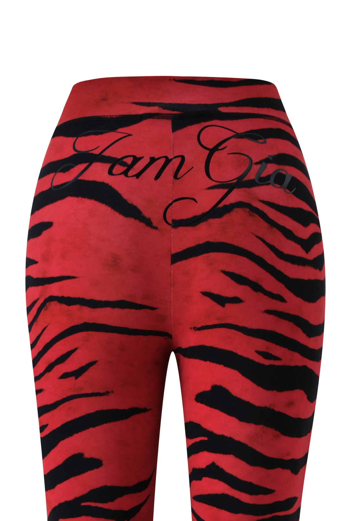 The BLARE TRACKPANT - RED WILD SIDE by I.AM.GIA is featured from the back, showcasing its striking red and black zebra print design with “I.AM.GIA” in black cursive printed across the waistband.