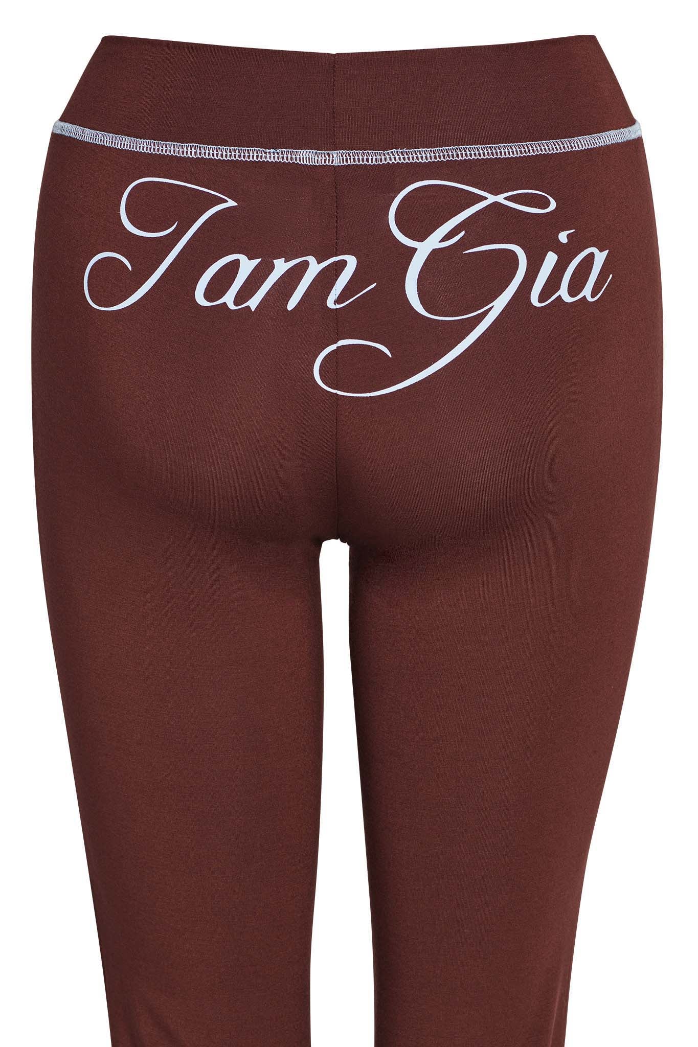 A close-up of the back of BLARE TRACKPANT - BROWN with "I.AM.GIA" written in large, white, cursive letters across the waistband.