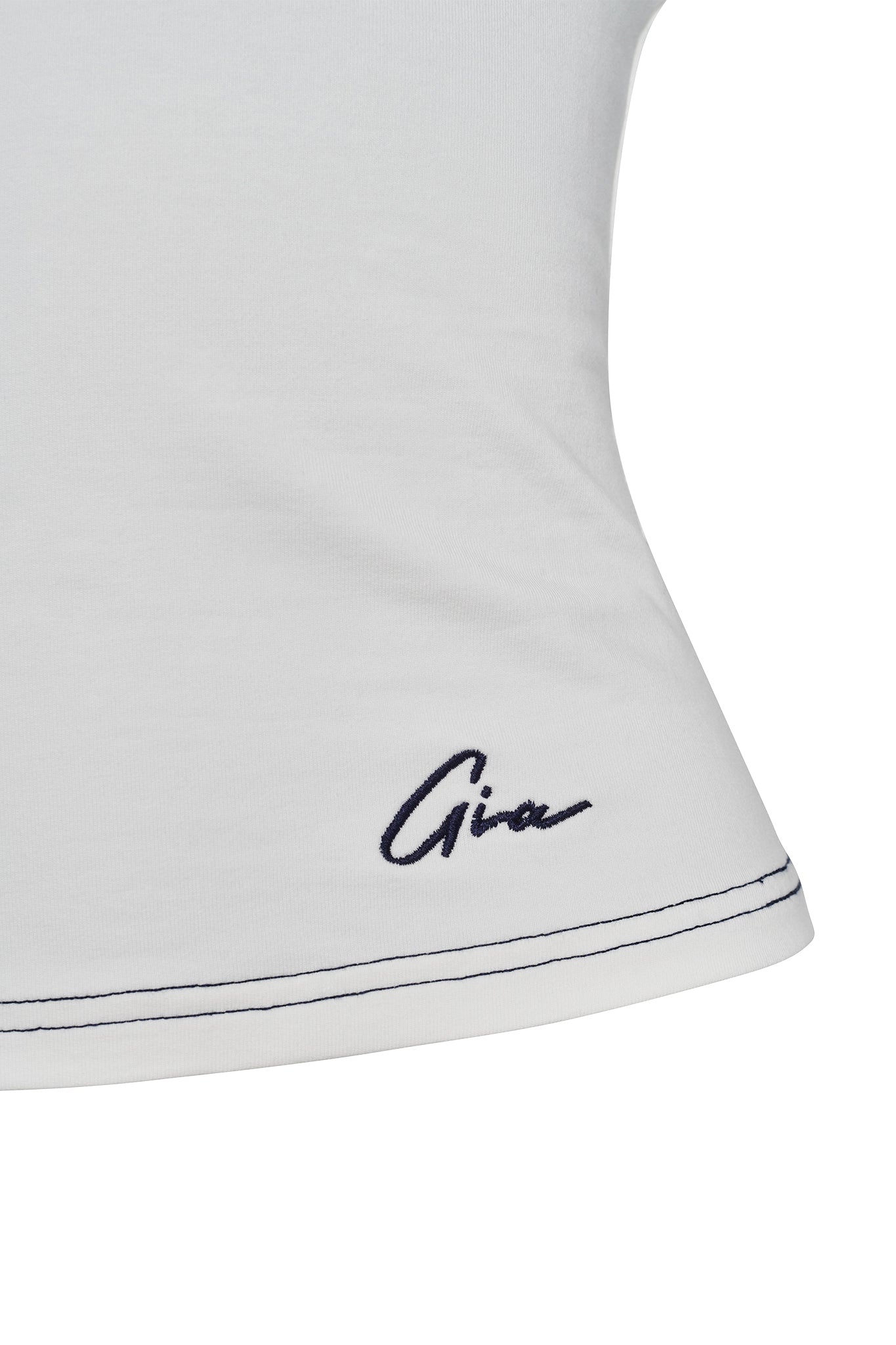 Close-up of the white fabric of the EDITA TOP, highlighting its blue stitching at the hem and a small embroidered signature that reads "Gia" in blue thread near the bottom edge, hinting at its stylish I.AM.GIA origin.