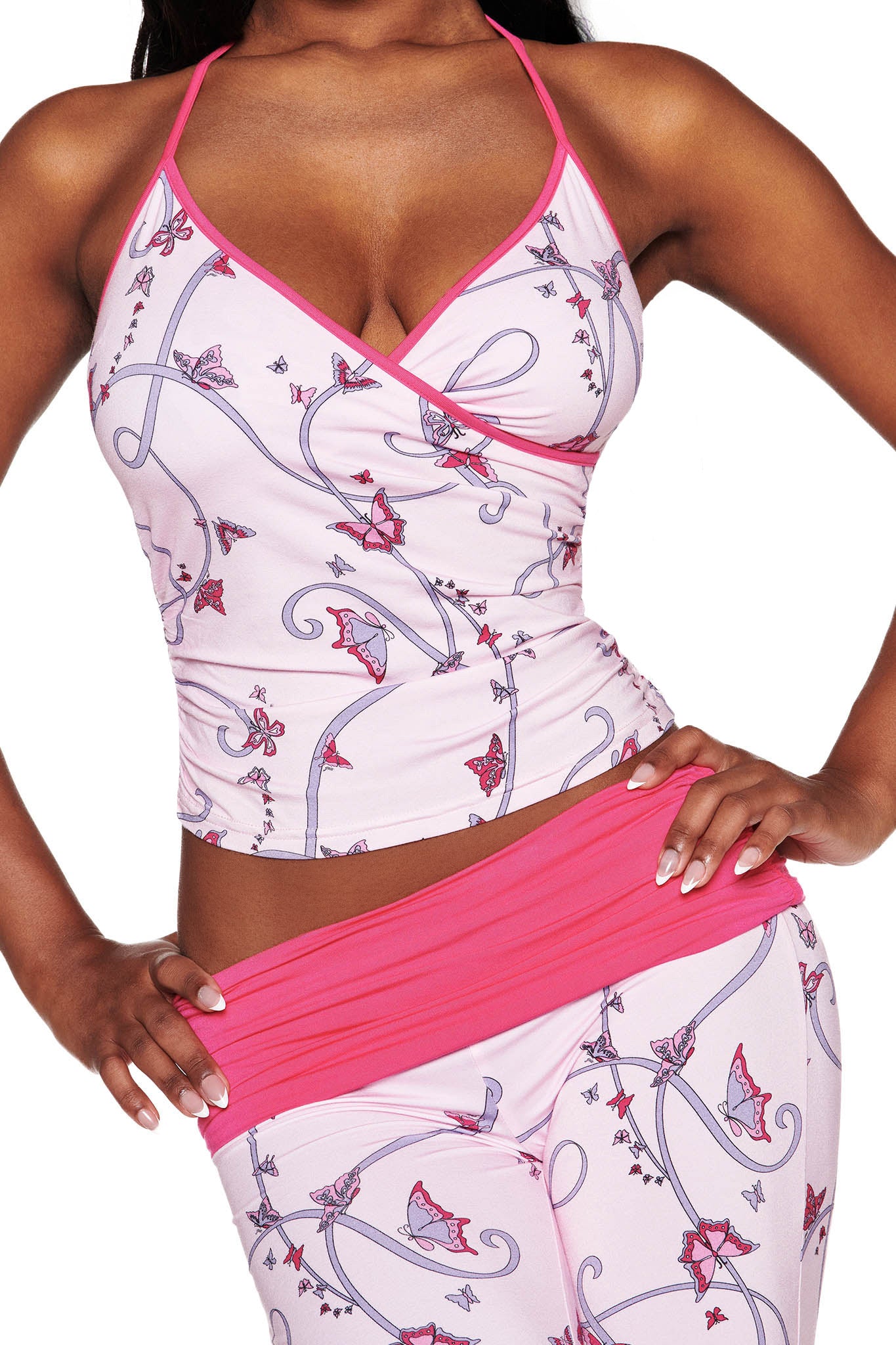 A person wears the I.AM.GIA JANNIS PANT in pink with a butterfly ribbon print and a pink waistband, along with a matching halter top. Only their torso and arms are visible against a white background.