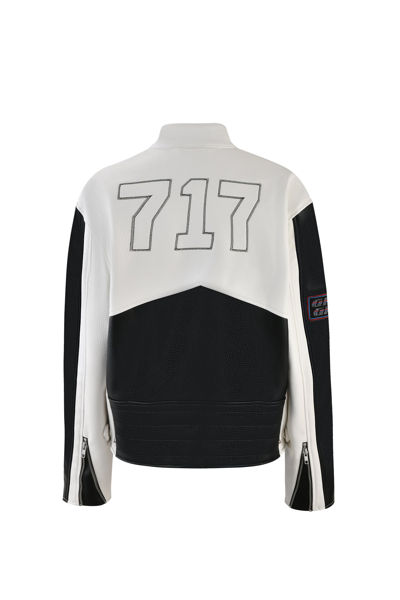 The ROXY JACKET - WHITE by I.AM.GIA is a black and white jacket with the number "717" prominently displayed in large font on the back. It features zippered sleeves, a small patch on the left arm, a high collar, and a mix of textured materials.