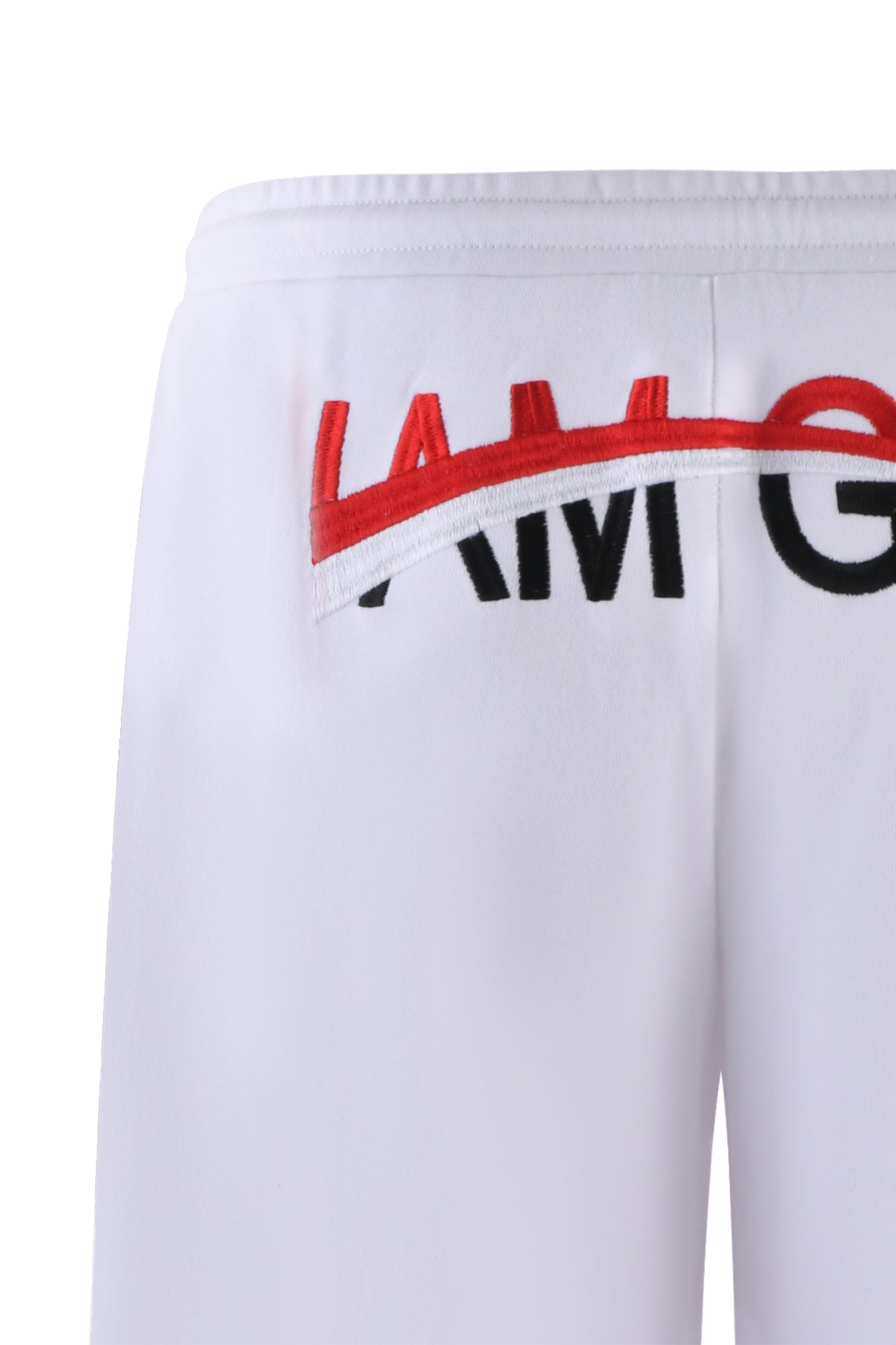 Close-up of the back of the JUSTINE PANT - WHITE by I.AM.GIA featuring partially visible embroidered text. The text "I AM G" is apparent, with part of "I AM" crossed out in red stitching, characteristic of I.AM.GIA's edgy style. The material appears smooth and slightly elastic.