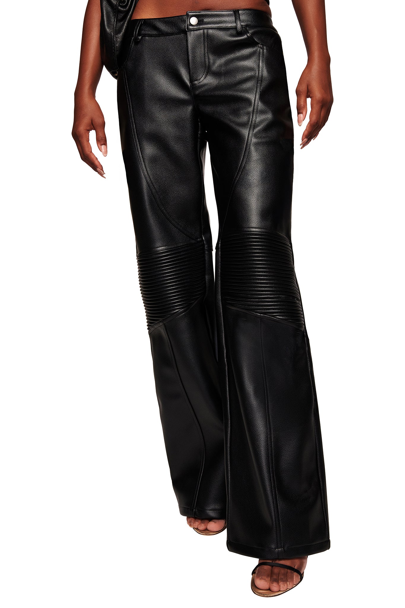 A person wearing the I.AM.GIA KRISTIE PANT in black—faux leather moto pants with ribbed detailing above the knees—paired with open-toe heeled sandals. Photo cropped from the waist down.