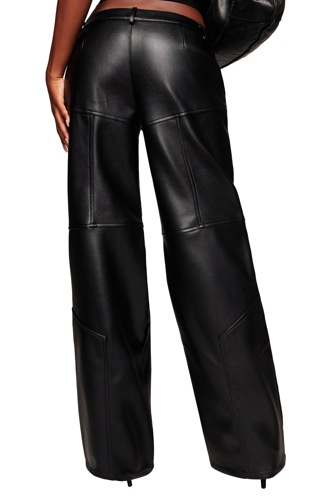 Back view of a person wearing the I.AM.GIA KRISTIE PANT in black—high-waisted, loose-fitting faux leather moto pants with visible seam details—standing against a white background.