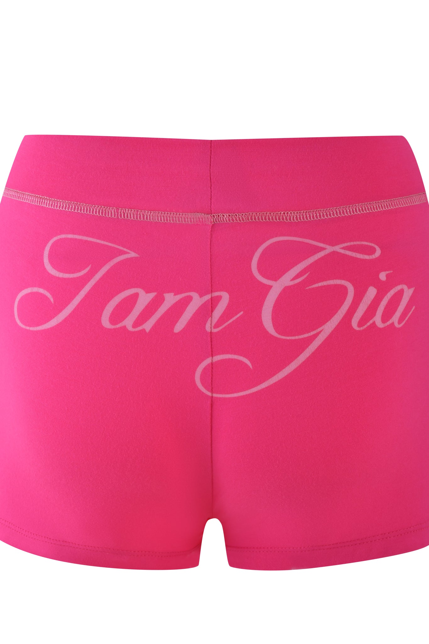 The BLARE SHORT - PINK from I.AM.GIA features a hot pink, bodycon fit with a white elastic waistband. It showcases the brand name in large, cursive letters across the back and is crafted from stretchy bamboo fabric for enhanced comfort and style.