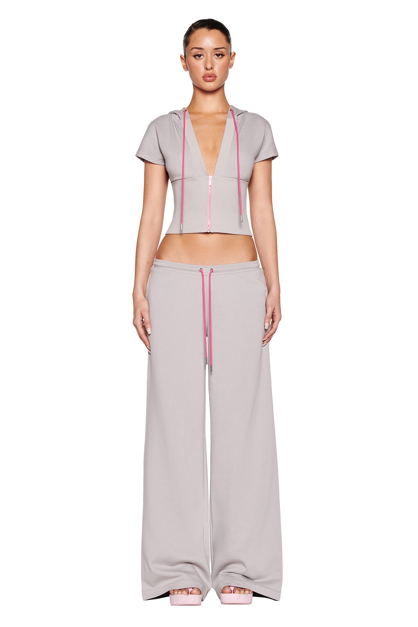 Someone in a gray hooded crop top and I.AM.GIA ARLO TRACK PANT - GREY : PINK stands against a white background.