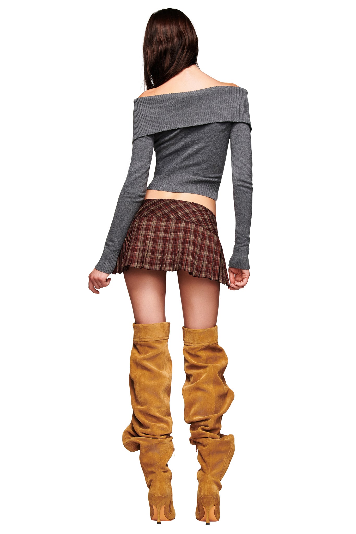 A woman with long brown hair faces away, wearing an off-the-shoulder gray sweater, tan slouchy boots, and the I.AM.GIA ROUX MINI SKORT in burgundy plaid.