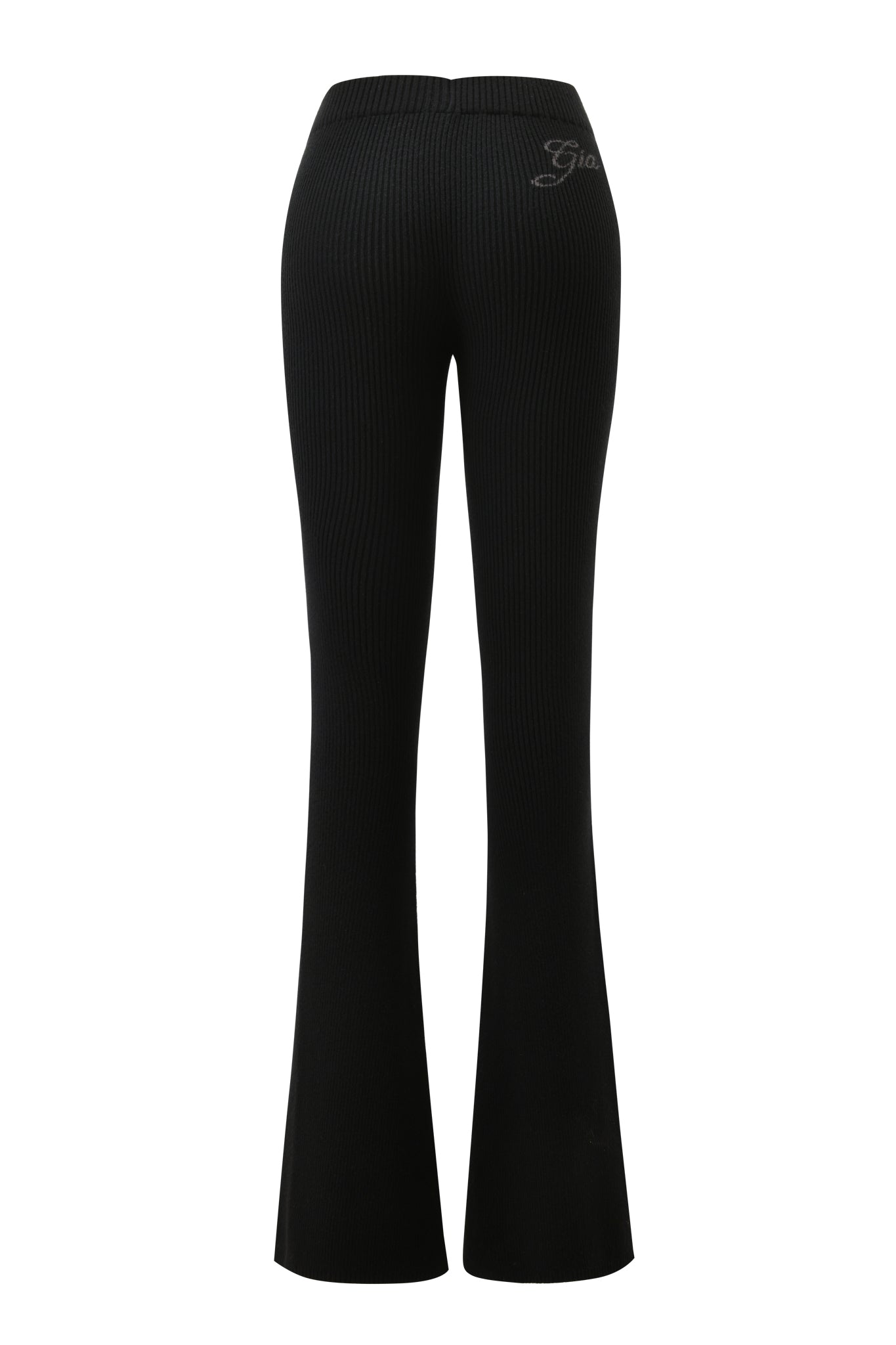 The BLARE KNIT TRACKPANT - BLACK by I.AM.GIA is shown from the back, featuring a mid-rise elastic waistband, flared bell-bottom legs, and small script embroidery on the right hip.