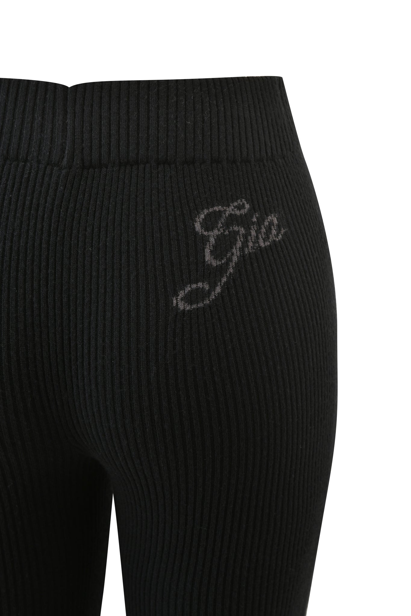 Close-up of the BLARE KNIT TRACKPANT - BLACK by I.AM.GIA, showcasing its black knit fabric, mid rise elasticated waistband, and "Gia" cursive embroidery on the right upper hip.