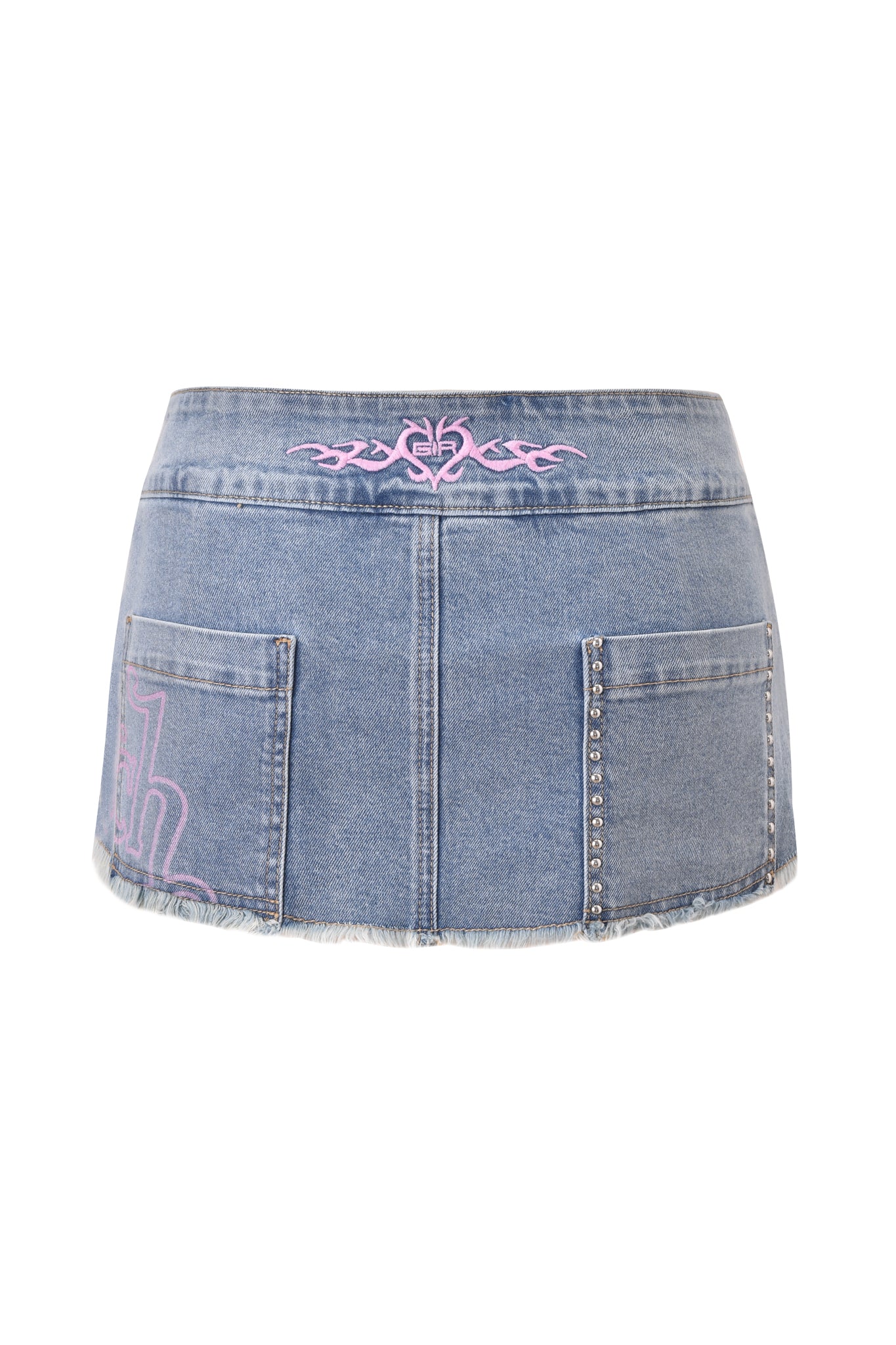 The I.AM.GIA X VON DUTCH SYNDRA DENIM MINI SKORT in light wash denim features a low rise waist, frayed hem, two front pockets, silver studs on the right pocket, and pink embroidery on the waistband and lower left side.