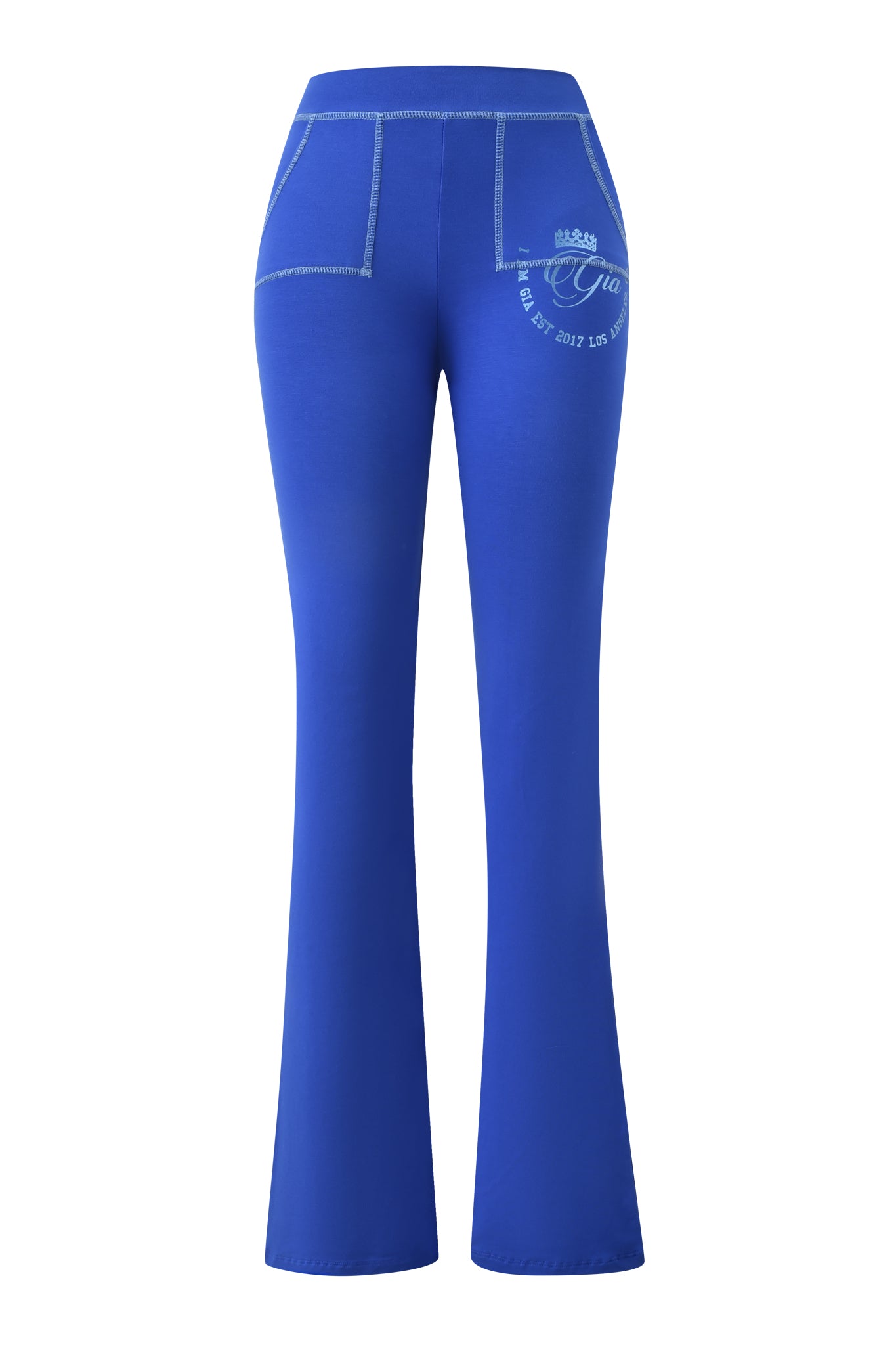 The I.AM.GIA BLARE FORM POCKET TRACKPANT - COBALT FOIL features bright cobalt blue, high-waisted flared pants with white stitching, two back pockets, a white printed crown and text on the right pocket, and soft bamboo fabric. Displayed on a white background.