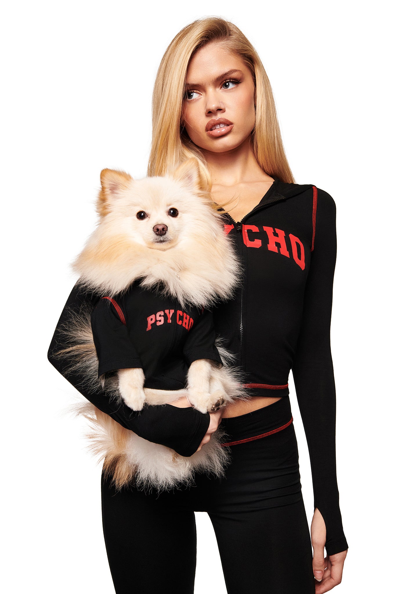 A woman with long blonde hair and her fluffy white dog both wear matching black "PSYCHO" hoodies—hers and the BLARE BEST FRIEND DOG HOODIE by I.AM.GIA—as they face forward against a white background.