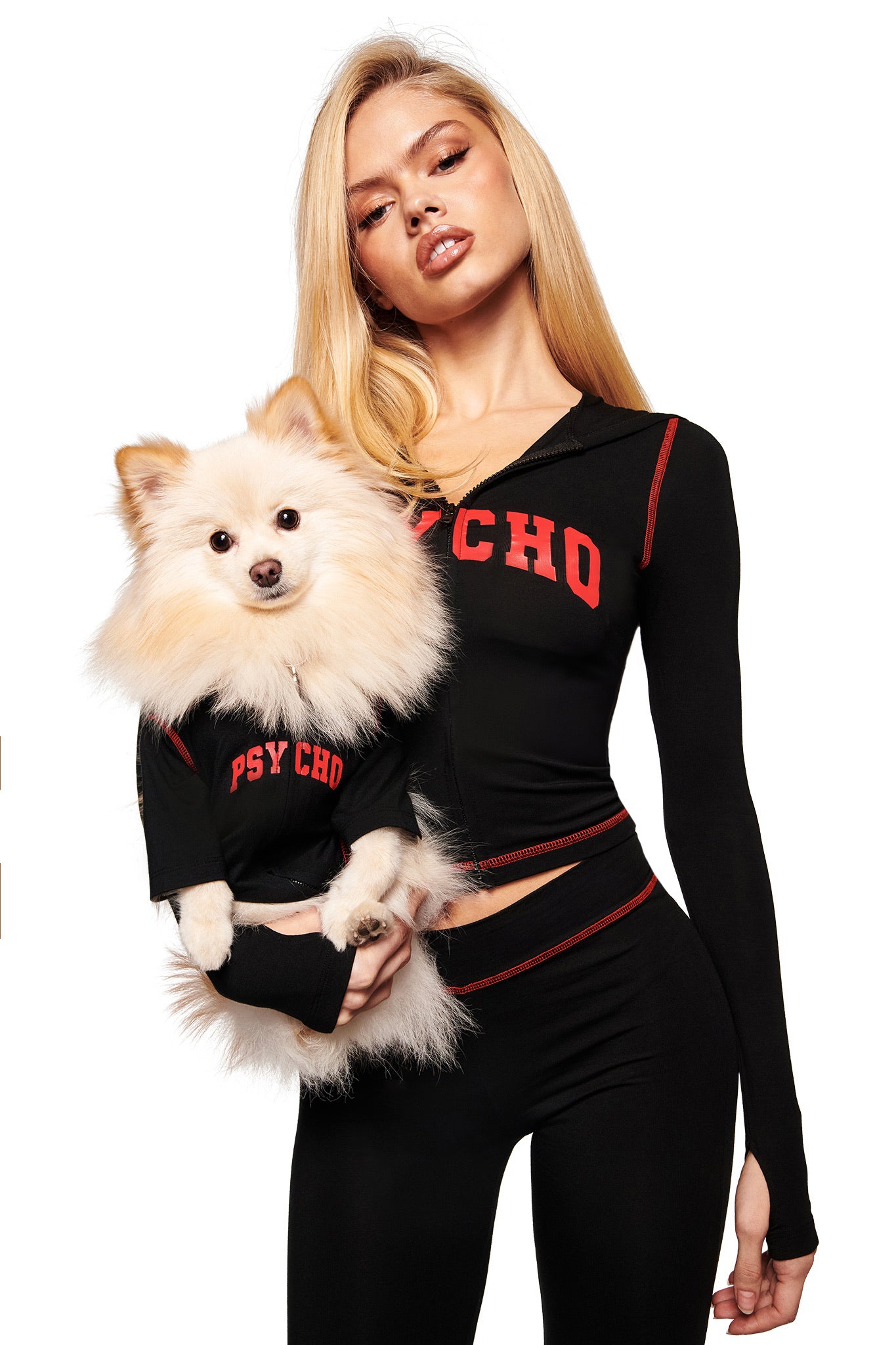 A woman poses with her dog in matching I.AM.GIA BLARE BEST FRIEND DOG HOODIE - BLACK PSYCHO outfits, each featuring bold red "PSYCHO" text, against a white background.