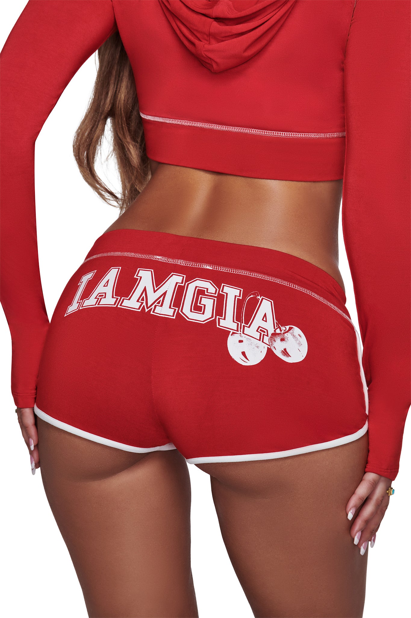 A person wearing the BLARE DOLPHIN SHORT - RED by I.AM.GIA and a matching hoodie, shown from the back. The shorts feature white trim with partially obscured “I.AM.GIA” branding and two cherry graphics, making this outfit perfect for summer beachwear.