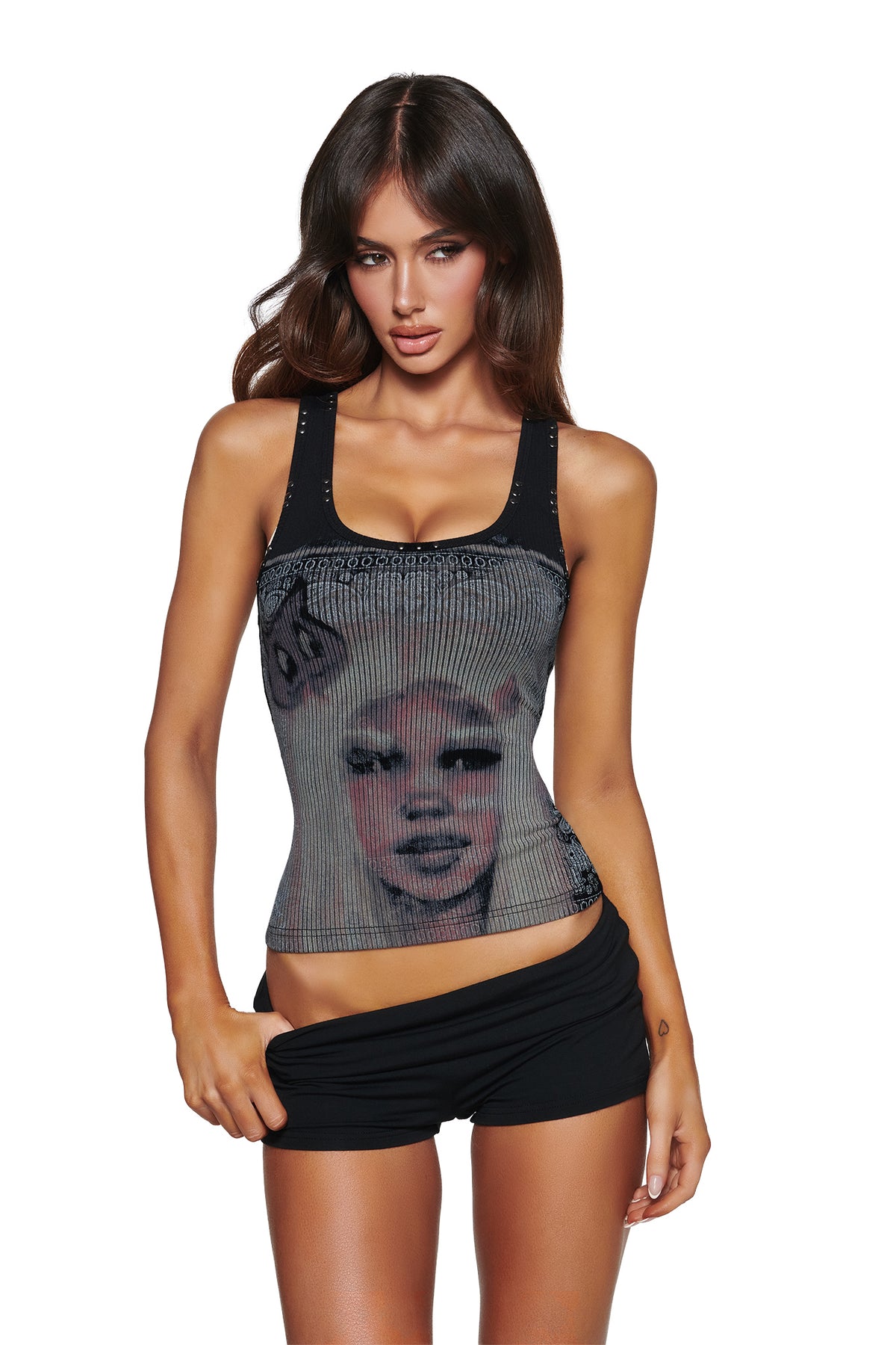 A woman with long brown hair poses against a white background wearing the I.AM.GIA T-REX INA TANK - BLACK, a sheer racer-style top with a printed face graphic, paired with black shorts.