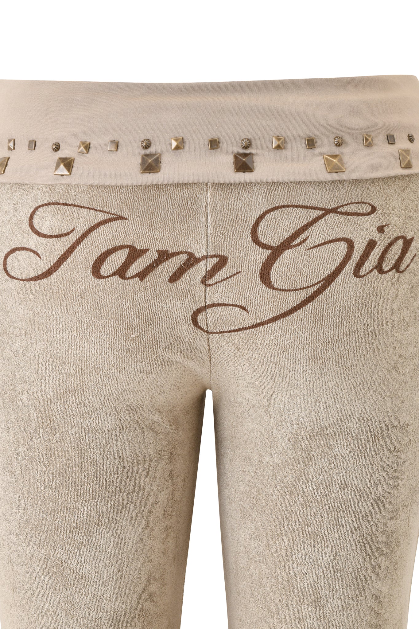 Close-up of the BLARE STUDDED TERRY PANT - STONE by I.AM.GIA, showcasing beige terry fabric with the brand logo in brown on the front waistband, embellished with square and round metallic studs. Inspired by the iconic Blare Trackpant.