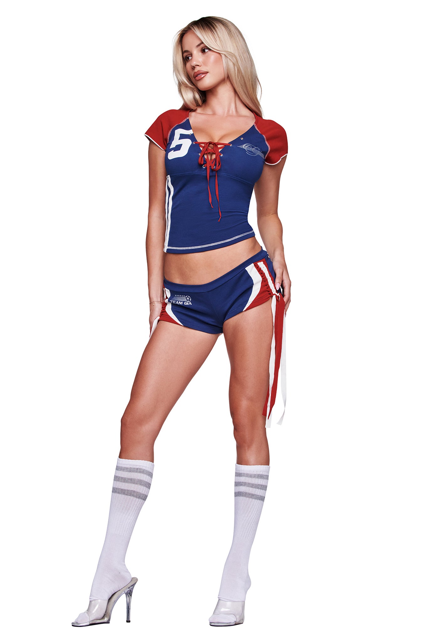 A woman poses in the I.AM.GIA NOVIA Lace-Up T-Shirt and Headband in navy, styled with sporty shorts, knee-high white socks, and clear high-heeled shoes.