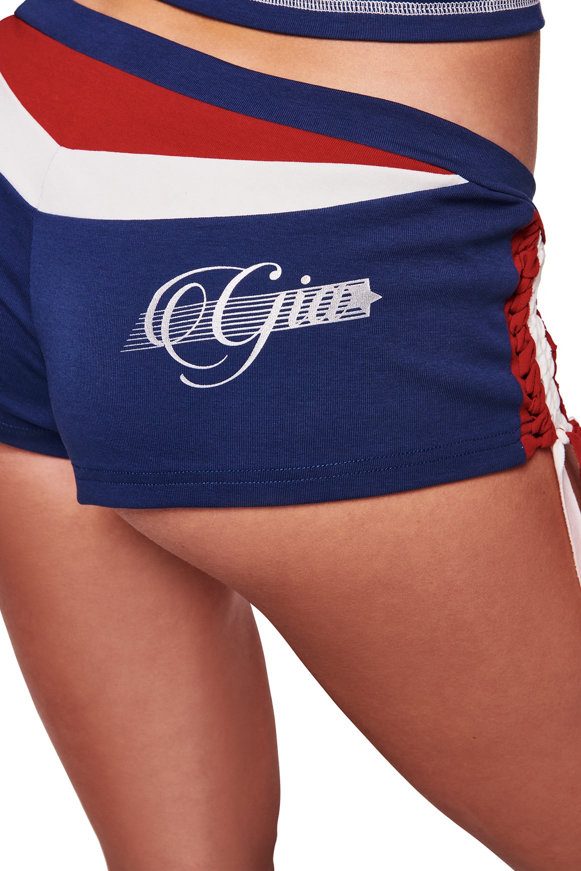 Someone wears the I.AM.GIA NOVIA MICRO SPORT SHORT - NAVY, blue stretch cotton shorts with red and white accents and "Gigi" scripted on the side, designed as low-rise and shown on the lower torso and upper thighs.