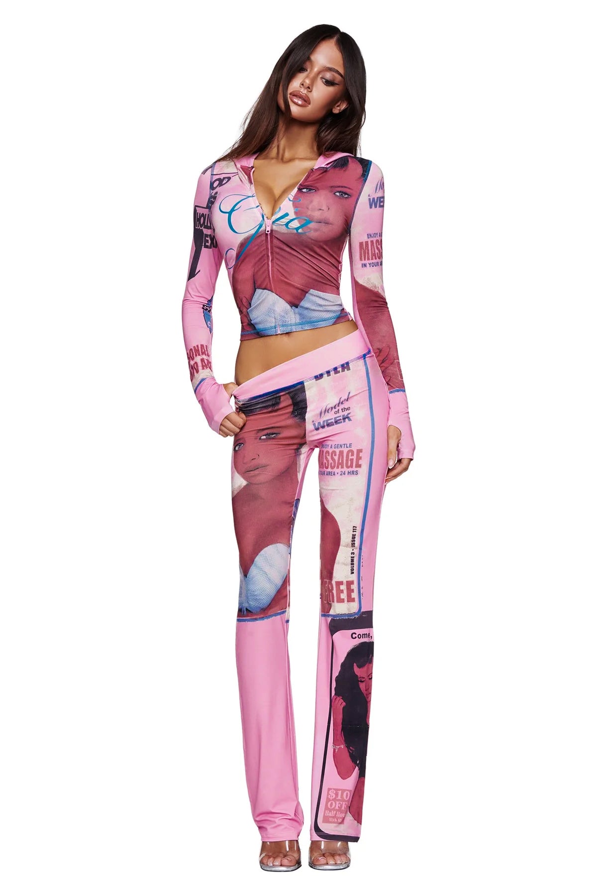 A woman wears the I.AM.GIA T-REX BLARE HOODIE in pink—a statement piece that showcases the brand’s bold, signature aesthetic with magazine-style graphic prints and portraits. She stands facing forward, one hand on her hip, her long brown hair left loose for an effortless finish.