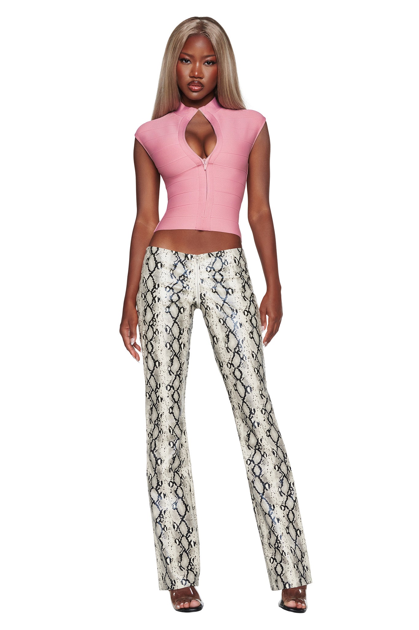 A woman stands wearing a pink cap-sleeve top with a keyhole cutout and the I.AM.GIA HENDRIX 2.0 PANT in Cream Snake, styled with open-toe heels. She has long, straight blonde hair.