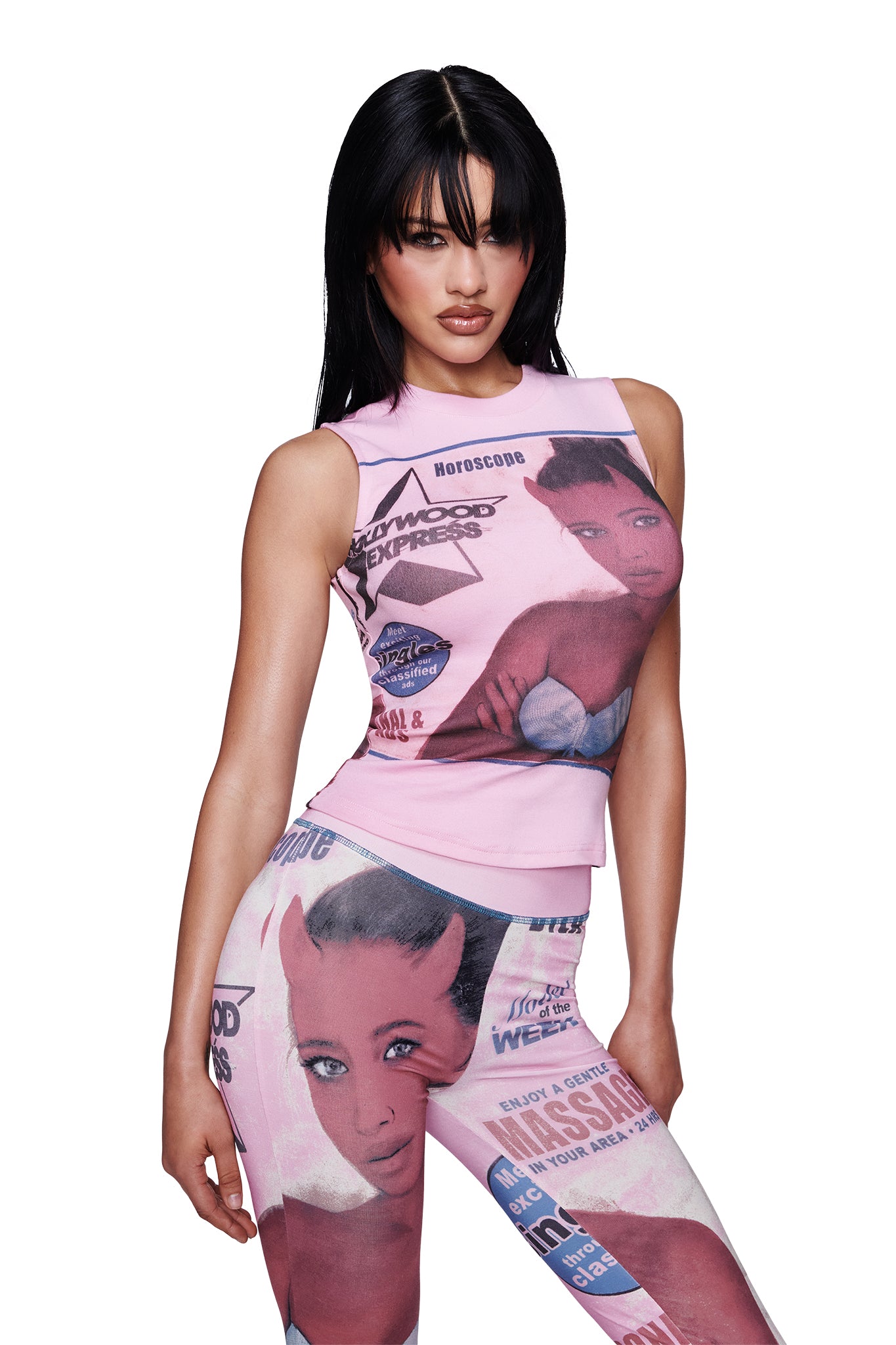 A woman with long dark hair models the I.AM.GIA T-REX COURTNEY TANK in pink, paired with matching magazine-style print pants featuring illustrated faces and text, posing confidently against a white background.