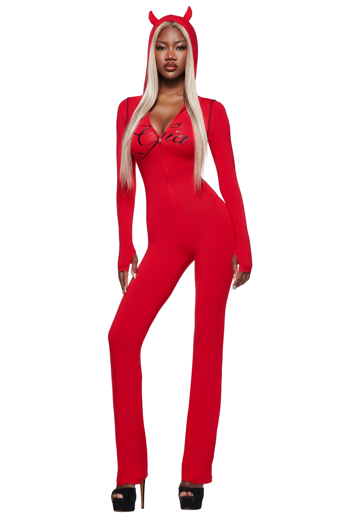A woman in the I.AM.GIA BLARE HORN JUMPSUIT - RED, styled with black platform heels and long blonde hair, poses confidently against a white background.