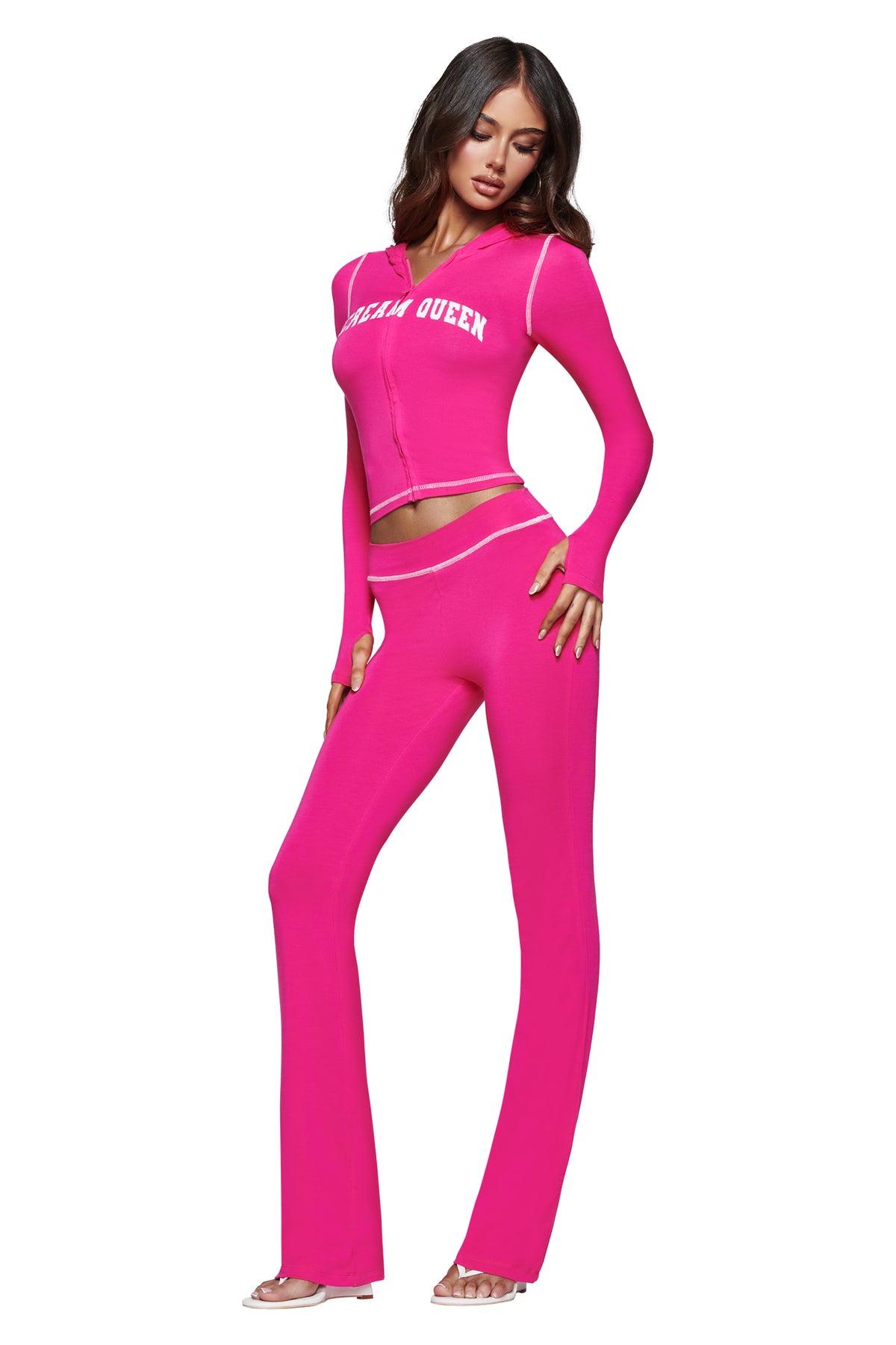 A woman stands confidently against a white background, wearing the I.AM.GIA BLARE HOODIE in Hot Pink Scream Queen—a vibrant, long-sleeve top crafted from soft bamboo fabrication—paired with matching flared pants.