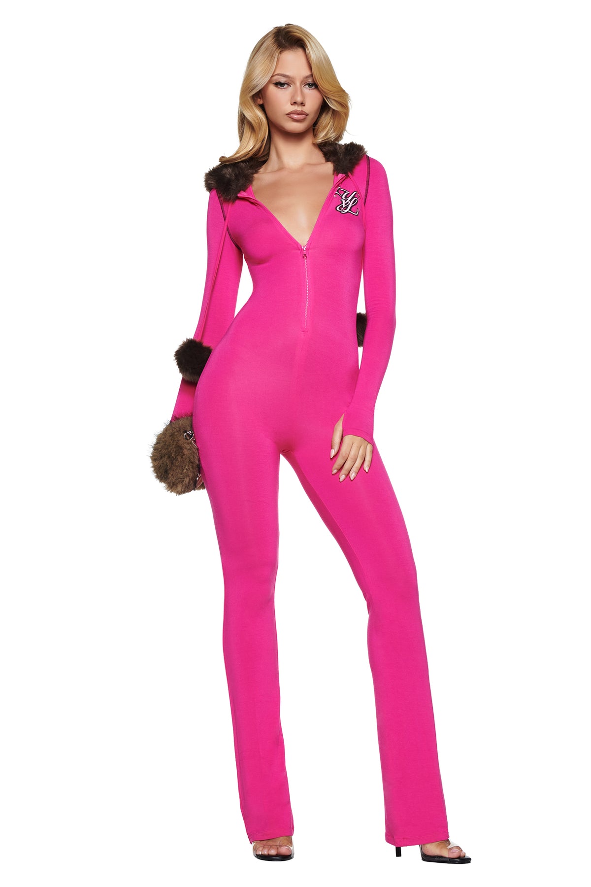 A woman wearing a bright pink YVL BLARE FUR LINED JUMPSUIT featuring a zip-up neckline, a faux fur hood, and matching fur-trimmed cuffs.