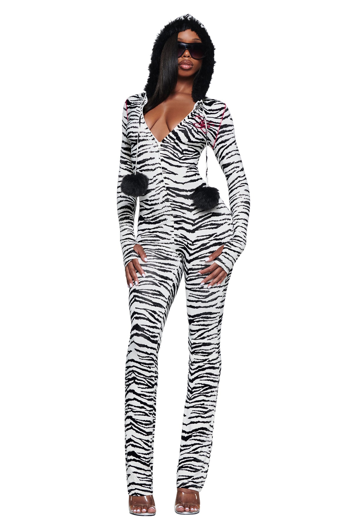 A person wearing a YVL BLARE FUR LINED JUMPSUIT - ZEBRA with a faux fur hood and two black pom-poms hanging from the front.