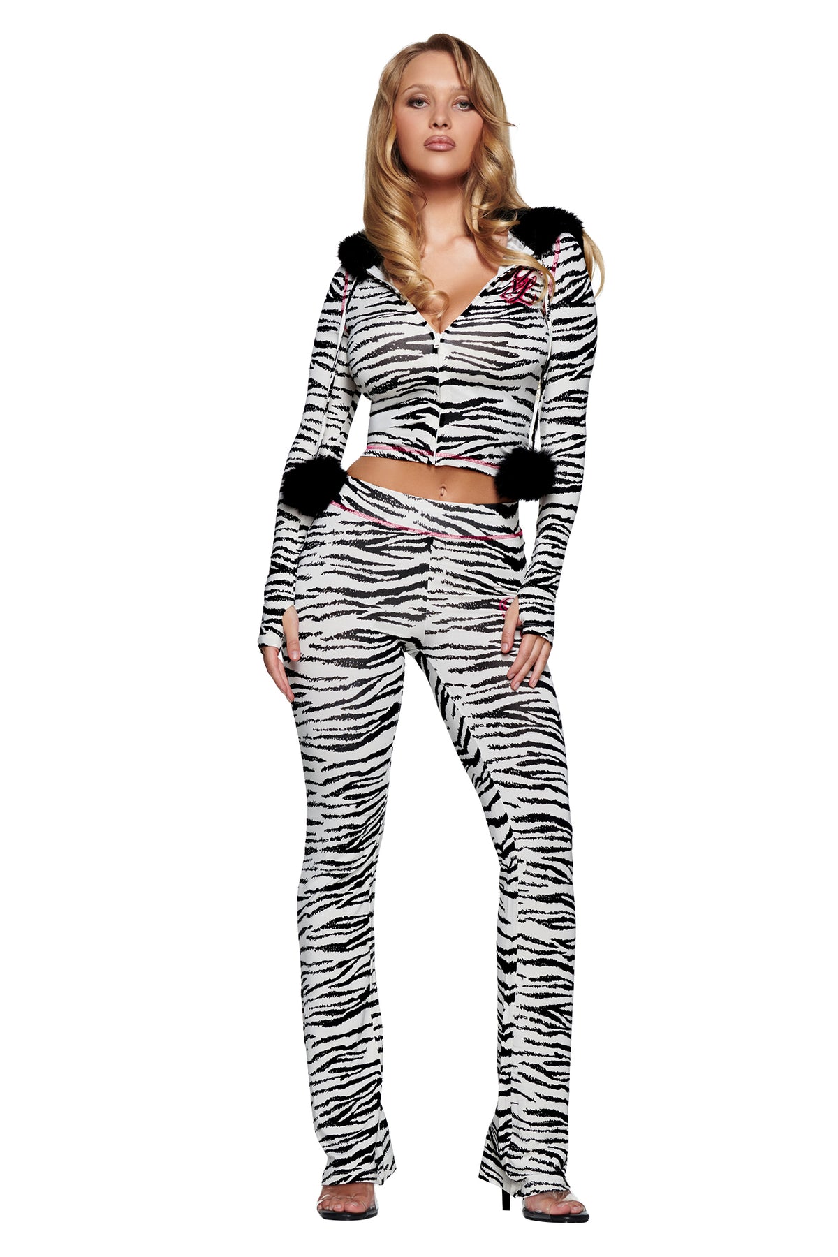 A woman wears a zebra-print zip-up hoodie with black pom-poms and matching YVL BLARE TRACKPANT - ZEBRA flared trackpants.