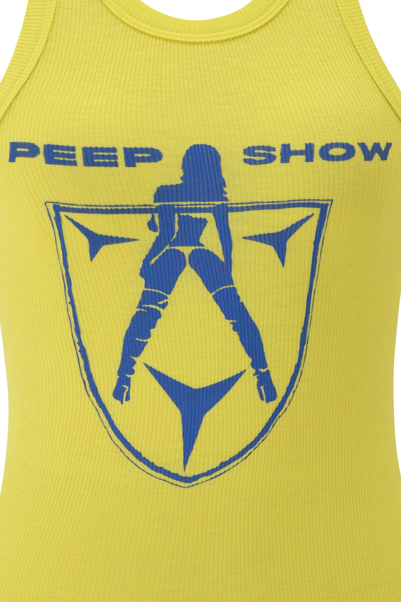 The I.AM.GIA PENELOPE TANK – BLUE PEEP SHOW is a yellow ribbed racer tank featuring blue "PEEP SHOW" text and a print of a woman in high boots above a star-filled shield.