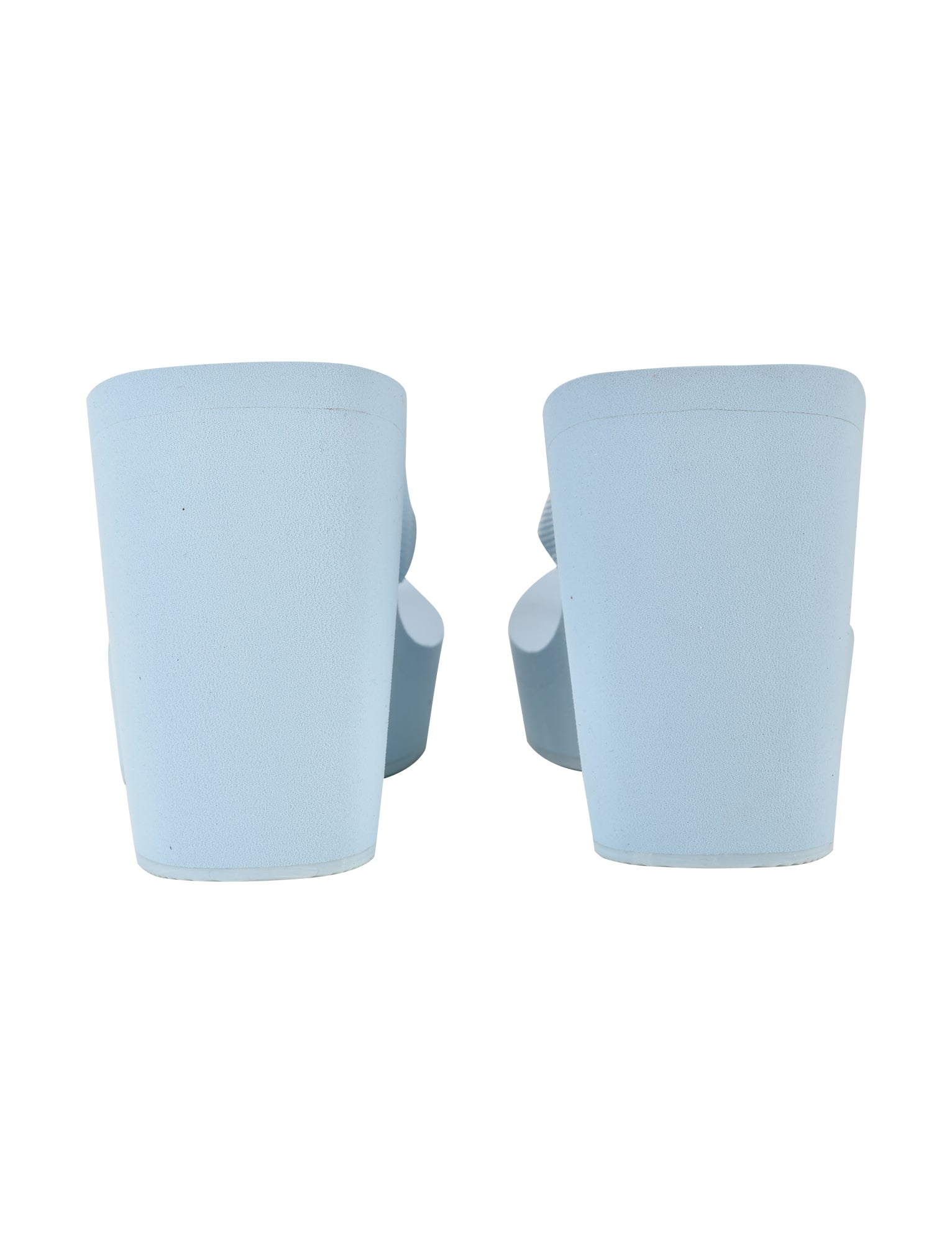 A pair of BABY BLUE SHELBY FLIP FLOPS by I.AM.GIA viewed from the back. The flip flops feature thick, high wedge soles and a simple, minimalist design. The color is uniform baby blue, and the material appears to be smooth and matte.