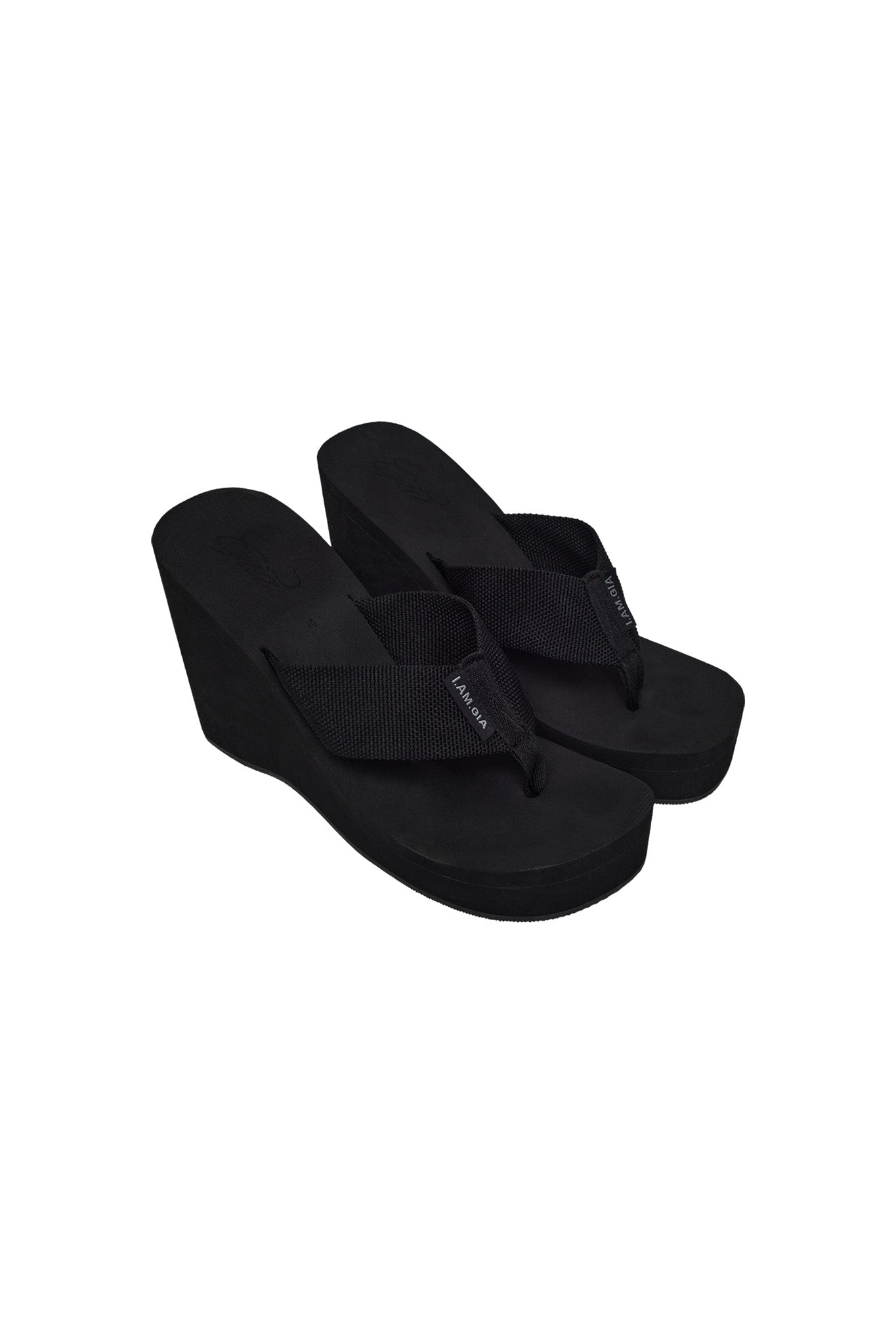 The SHELBY FLIP FLOP - BLACK by I.AM.GIA embodies the brand's edgy aesthetic with its slightly elevated wedge heel that adds height while maintaining the casual style of traditional flip flops. The wide straps, crafted from a textured material, add extra flair to this chic pair of black wedge flip flops.
