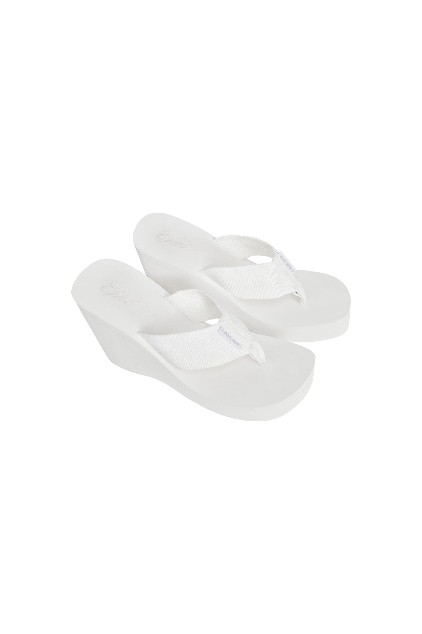 The SHELBY FLIP FLOP - WHITE by I.AM.GIA are casual wedge sandals with textured white straps and slightly elevated soles for added height. These comfortable flip-flops offer a clean, minimalistic look that’s perfect for any laid-back outing.
