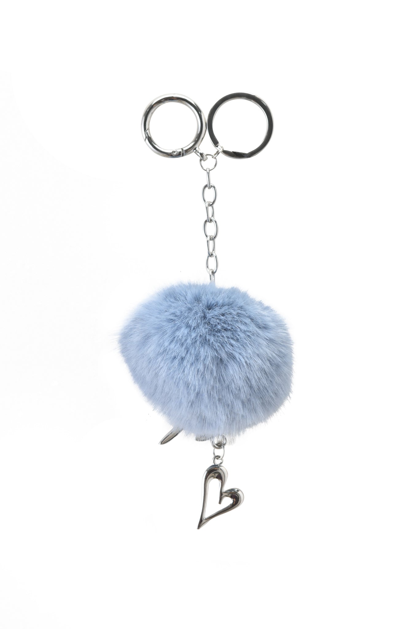 The I.AM.GIA LARSA KEYCHAIN - BLUE showcases a silver chain with a fluffy light blue faux fur pom-pom and a silver heart charm, set against a white background.