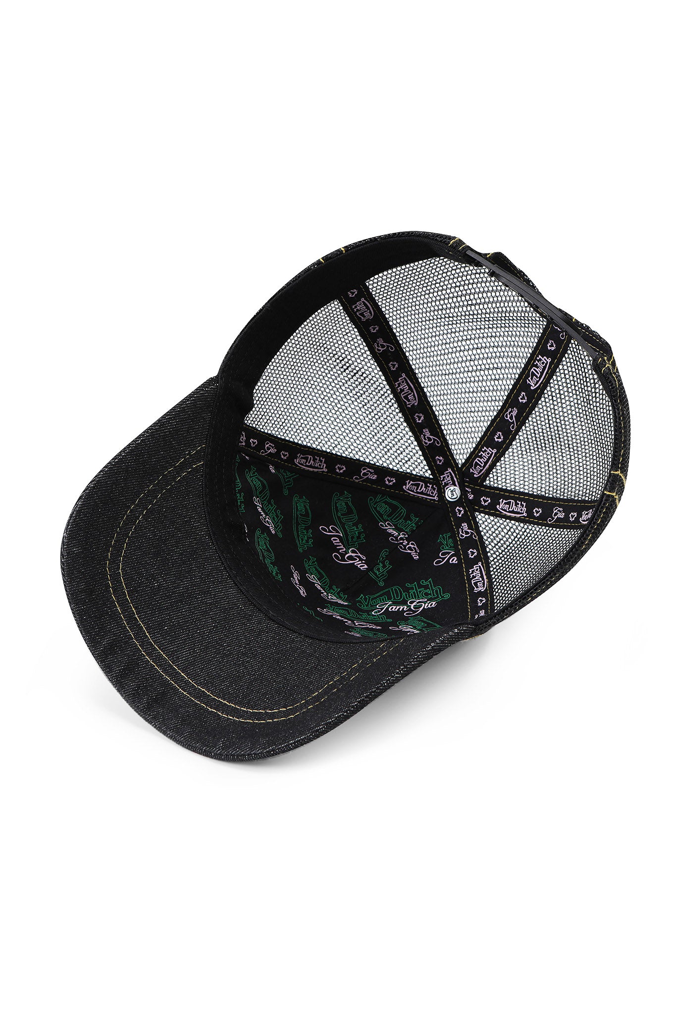 The I.AM.GIA X VON DUTCH TRUCKER HAT - INDIGO DENIM shown from below reveals its interior stitching, black mesh panels, and the inside crown’s printed fabric with green and white designs.