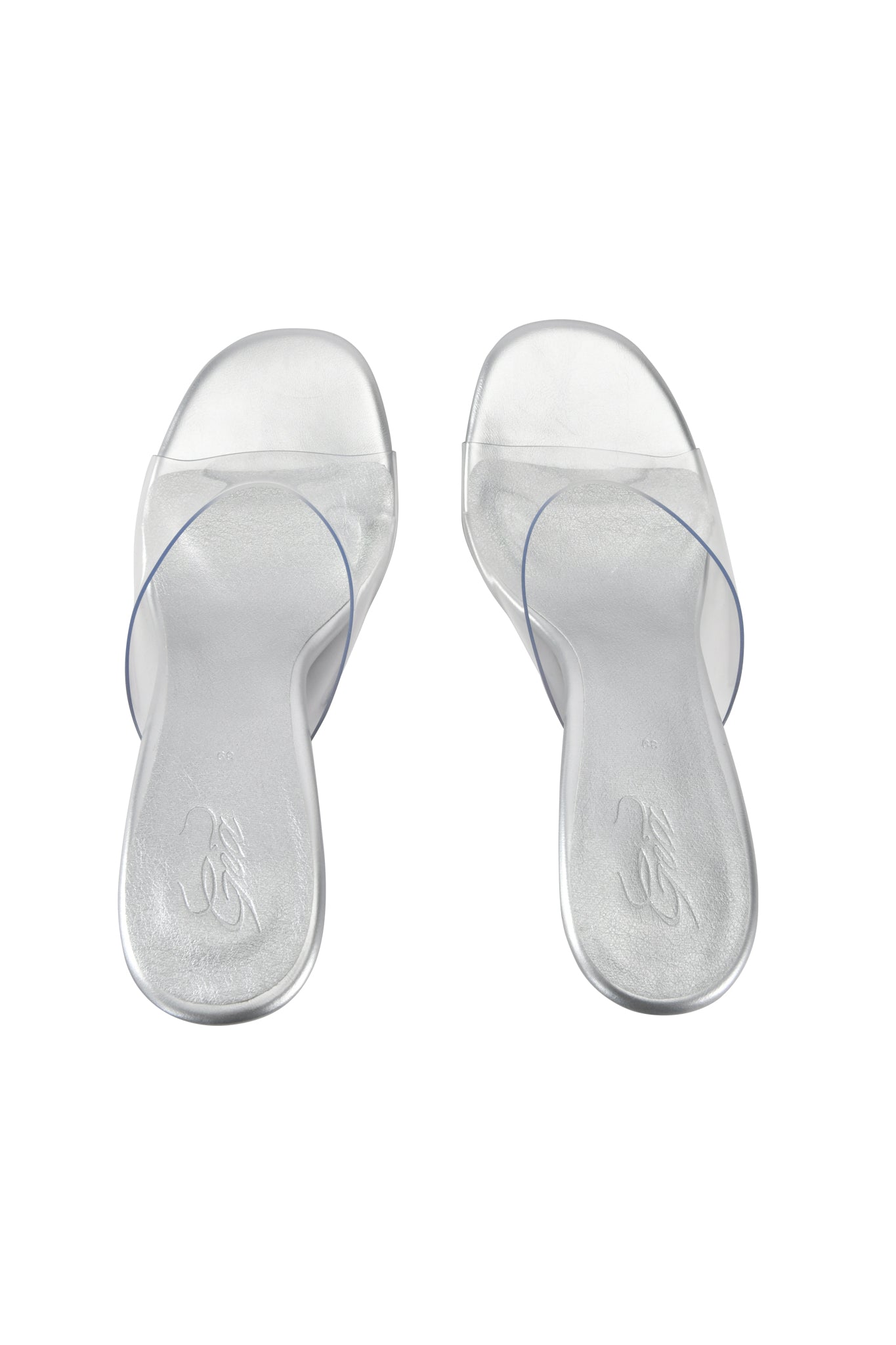 The I.AM.GIA RHEA CLEAR WEDGE HEEL - TRANSPARENT features sculpted wedge mule sandals with clear vinyl straps and a transparent heel, displayed on a white background.