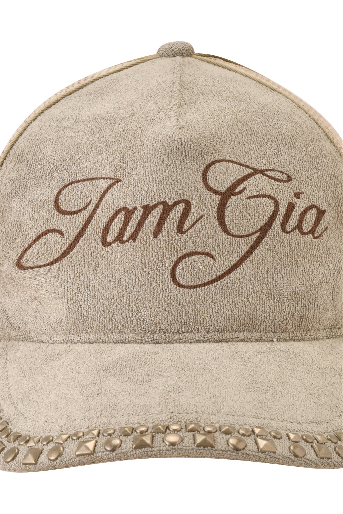 The ISSHA TERRY HAT - STONE by I.AM.GIA is a beige suede hat with "I am Gia" in brown cursive on the front and decorative studs on the brim, combining classic snapback trucker style with chic details.