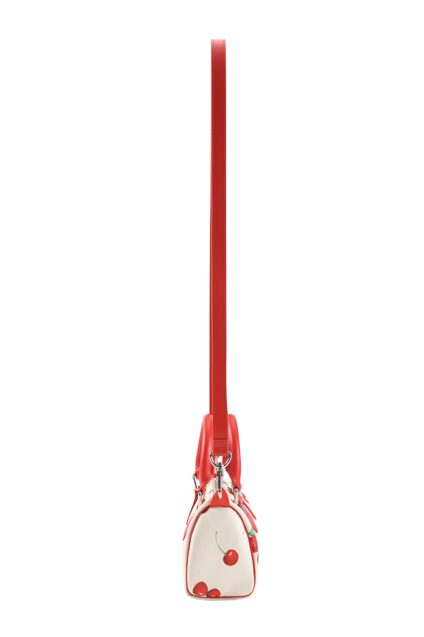 Side view of the I.AM.GIA NIKA MINI BAG - CHERRY ON TOP, a white mini barrel purse with a bold cherry print and a long red strap extending vertically.