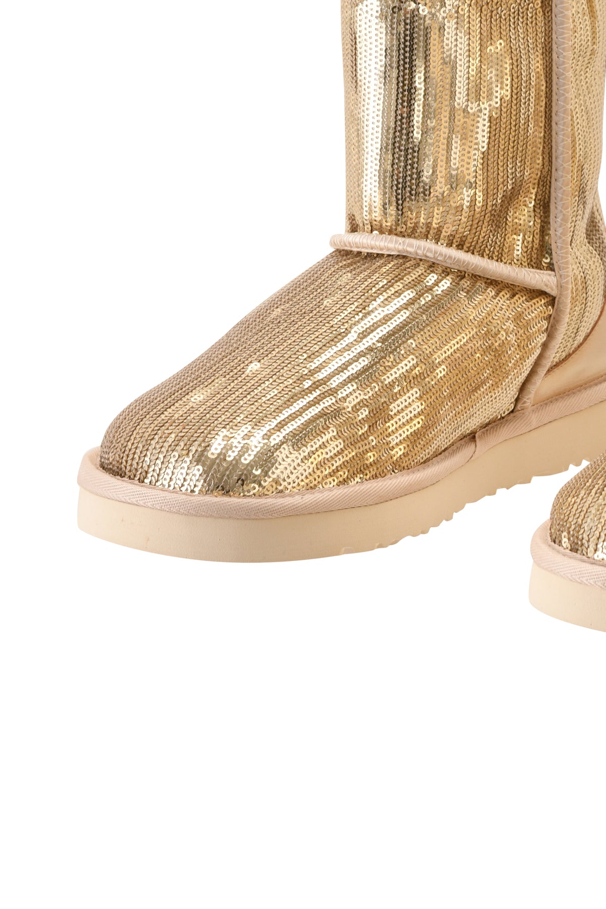 A close-up of the ELVIRA SEQUIN BOOT - GOLD by I.AM.GIA, featuring a pair of mid-calf, gold sequin-covered boots with light beige soles and a cozy faux fur lining, shown against a white background.