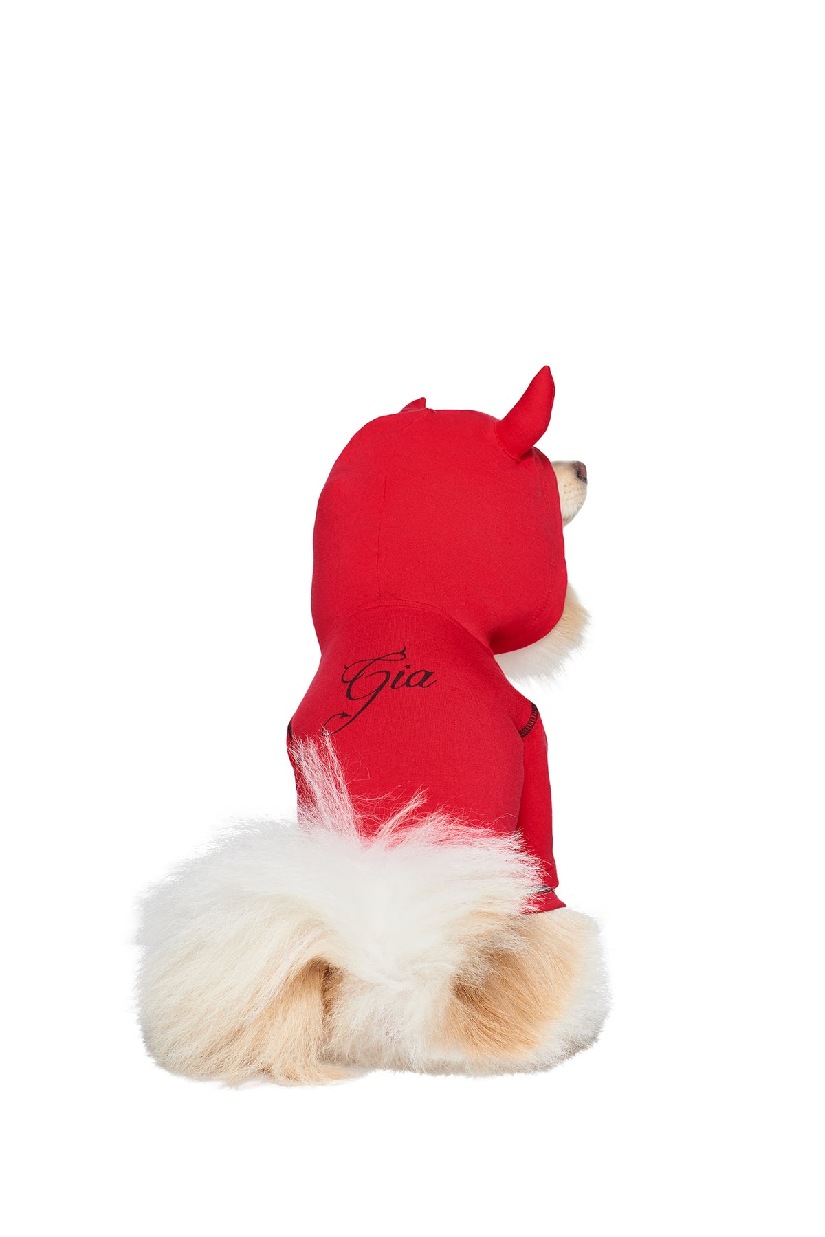 A fluffy, light-furred dog sits facing away, wearing the I.AM.GIA T-REX BEST FRIEND BLARE HORN DOG HOODIE - RED with little devil horns and ears.