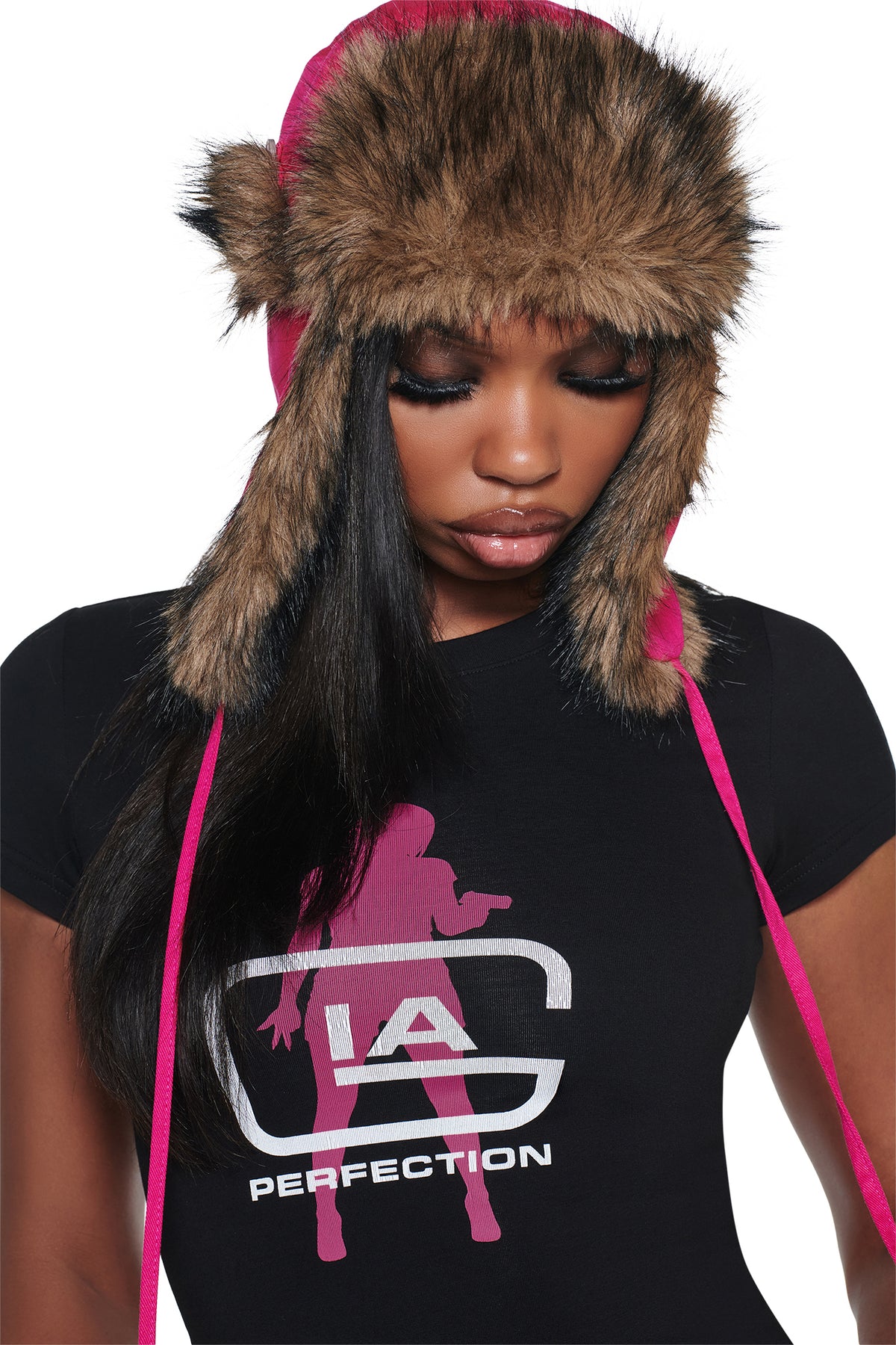 A person wearing an I.AM.GIA YVL FUR TRAPPER HAT - PINK, featuring brown faux fur trim and long pink ties.